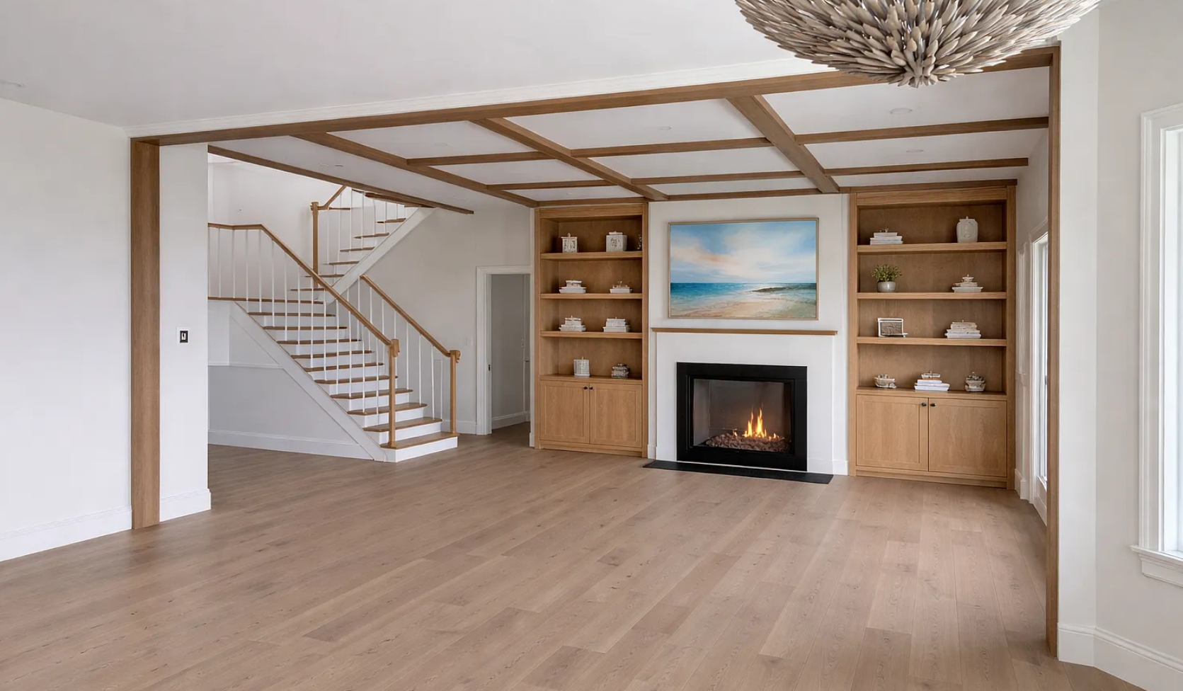 Great room with a coffered wood-grid ceiling, paired oak bookcases flanking a gas fireplace, and a staircase visible to the upper floor.