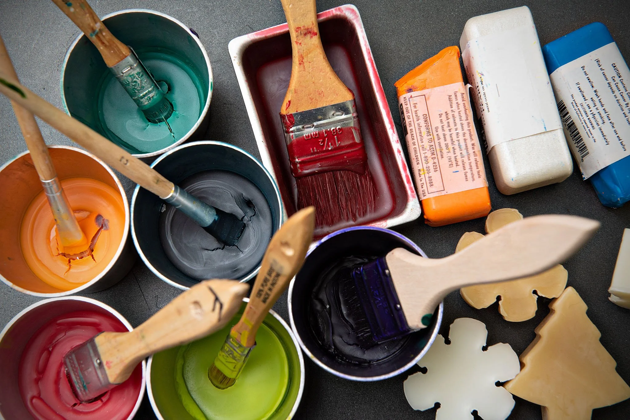 Analysis of various open paint cans with brushes and soap bars on a black surface.