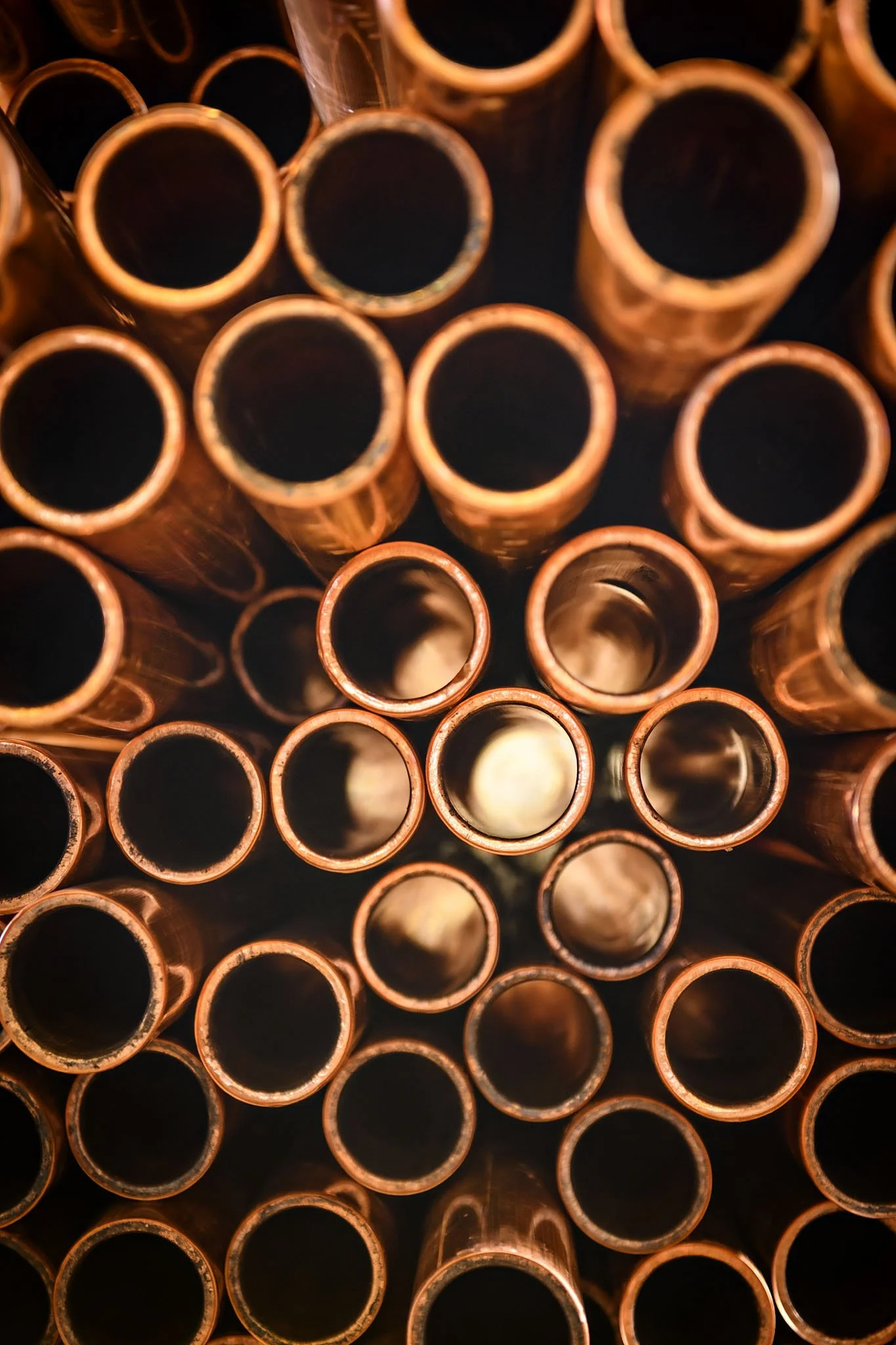 Close-up view of multiple copper pipes arranged vertically, showing their open ends facing the camera.