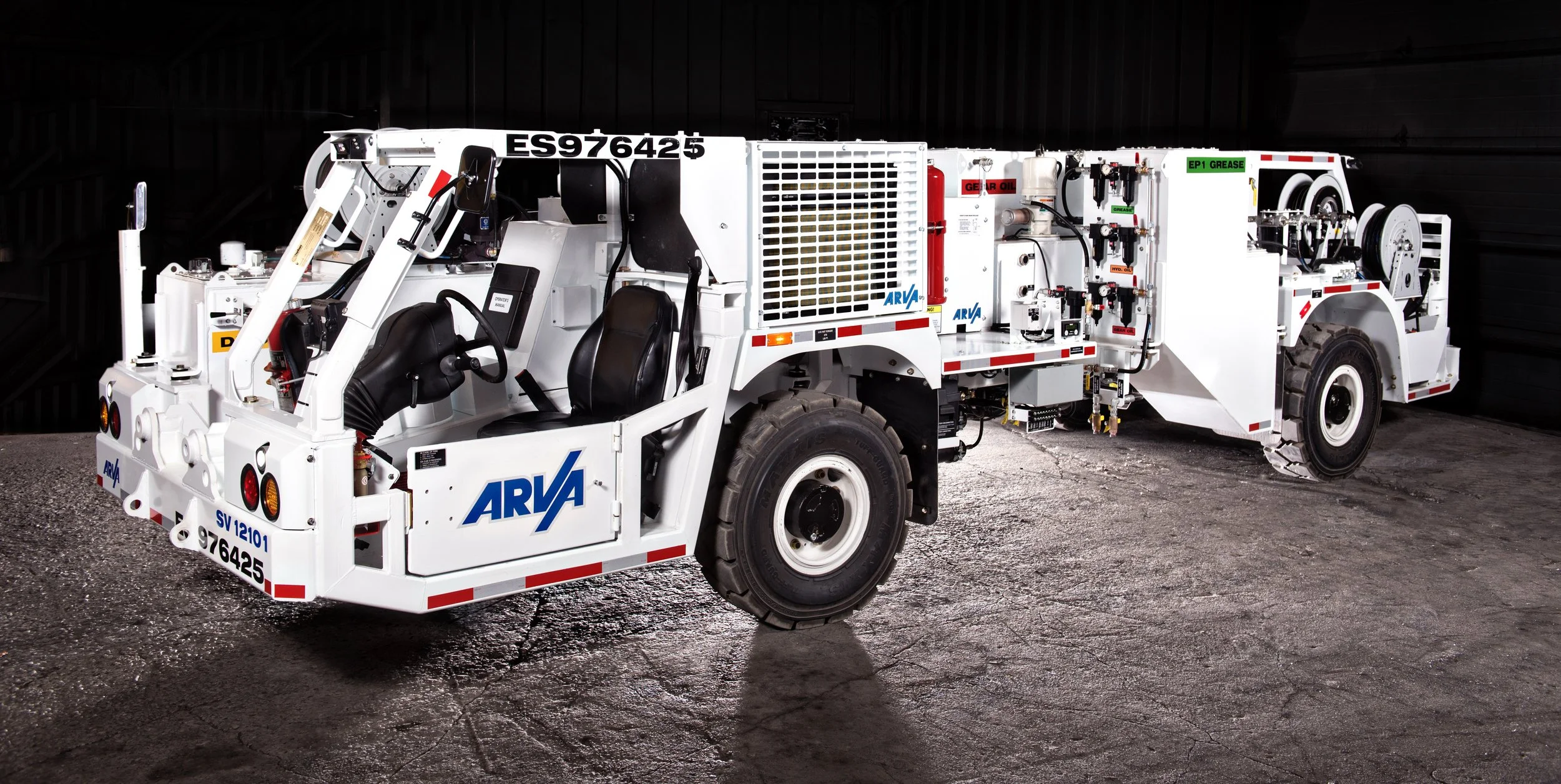 A white airport pushback tug with ARVA branding on the side, parked on a concrete surface inside a dark indoor space.