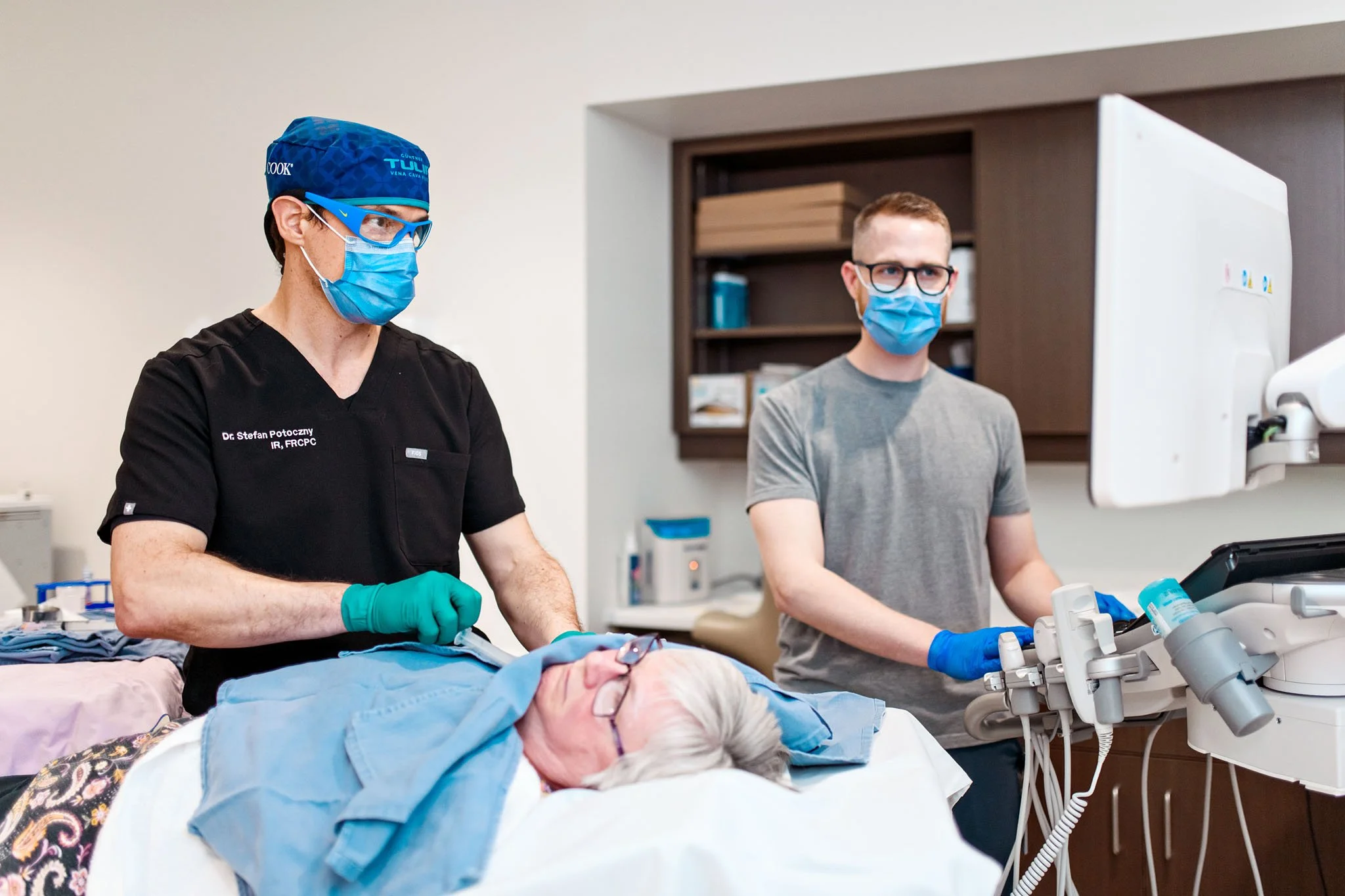 Medical professionals perform surgery in an operating room, with a patient lying on the operating table.