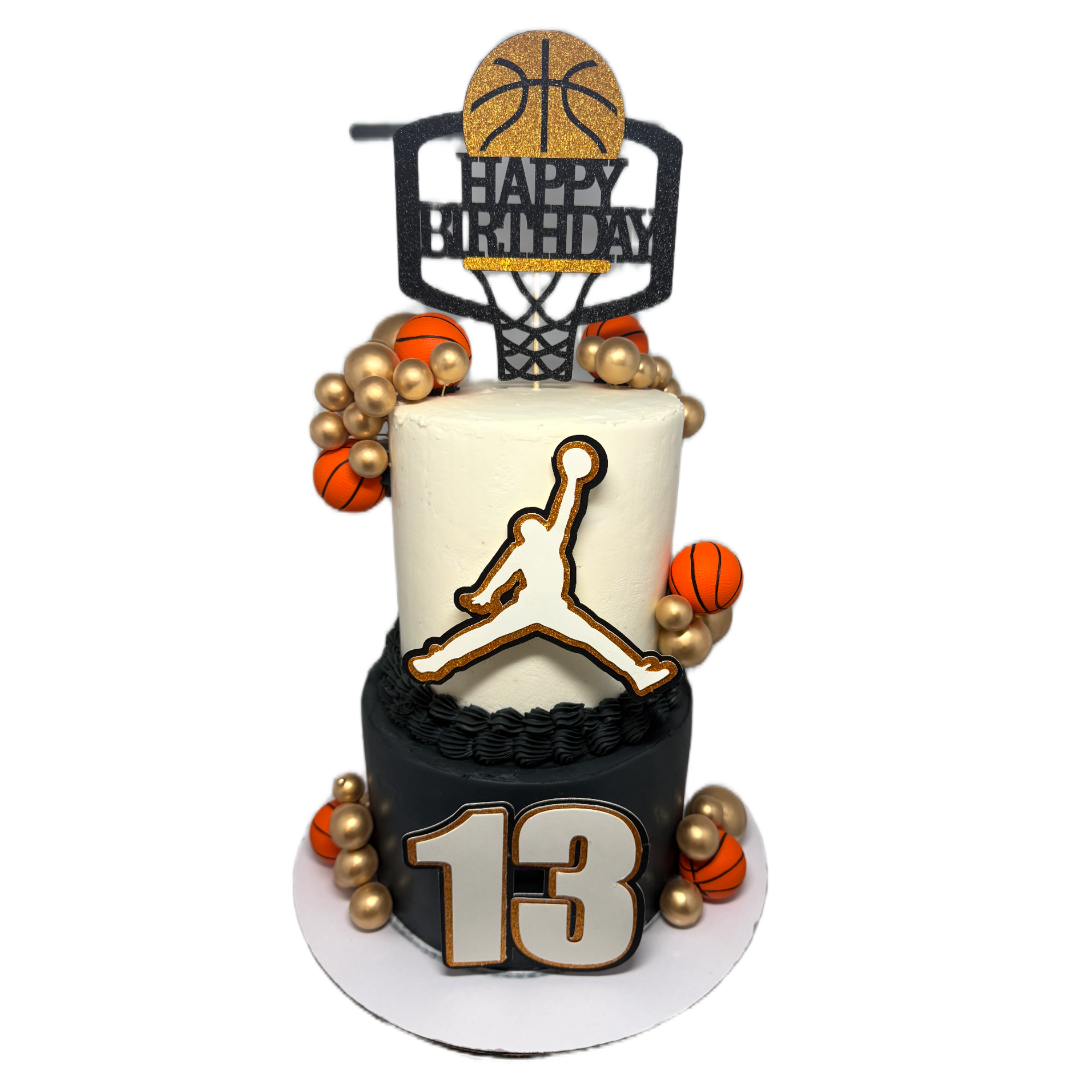 A Jordan basketball-themed birthday cake with a basketball hoop topper that says 'Happy Birthday' and a gold basketball, with orange and gold basketball decorations around the cake.