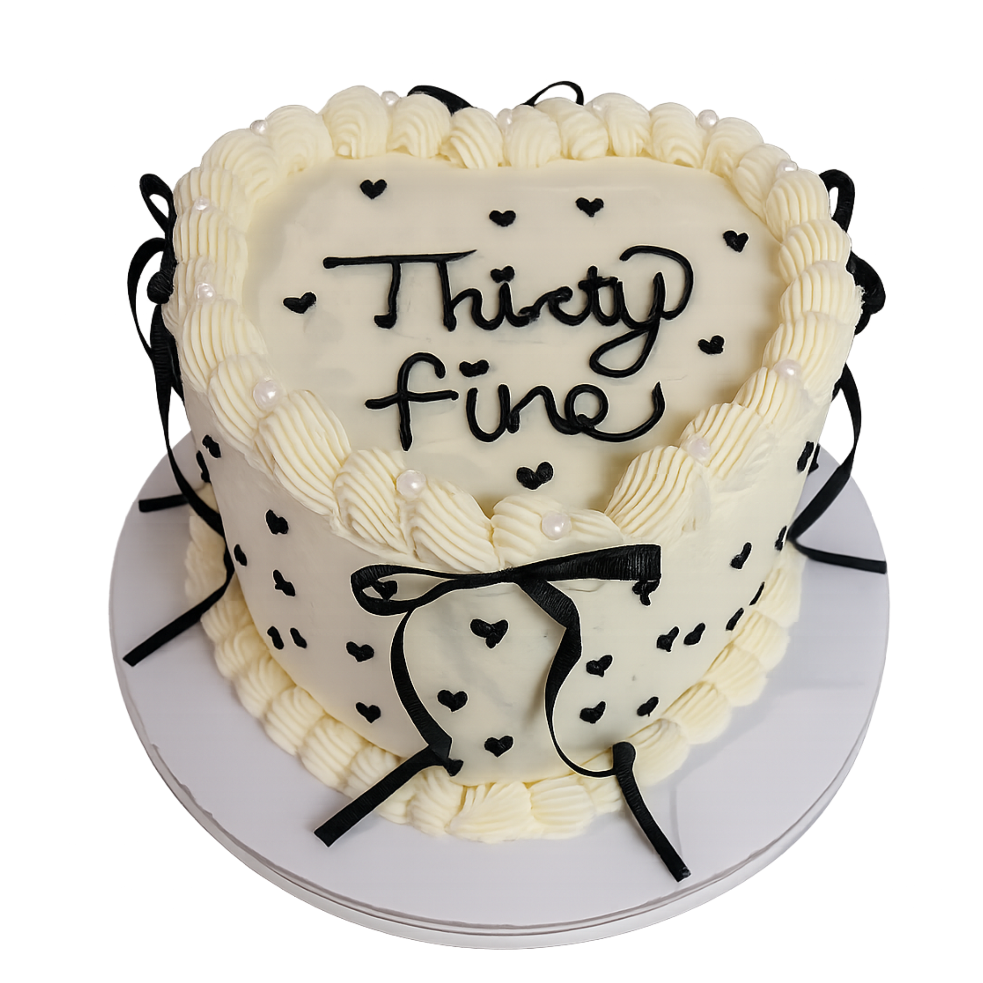 Heart-shaped cake decorated with white icing, black string accents, small black hearts, and the words 'Thank you' written on the front.