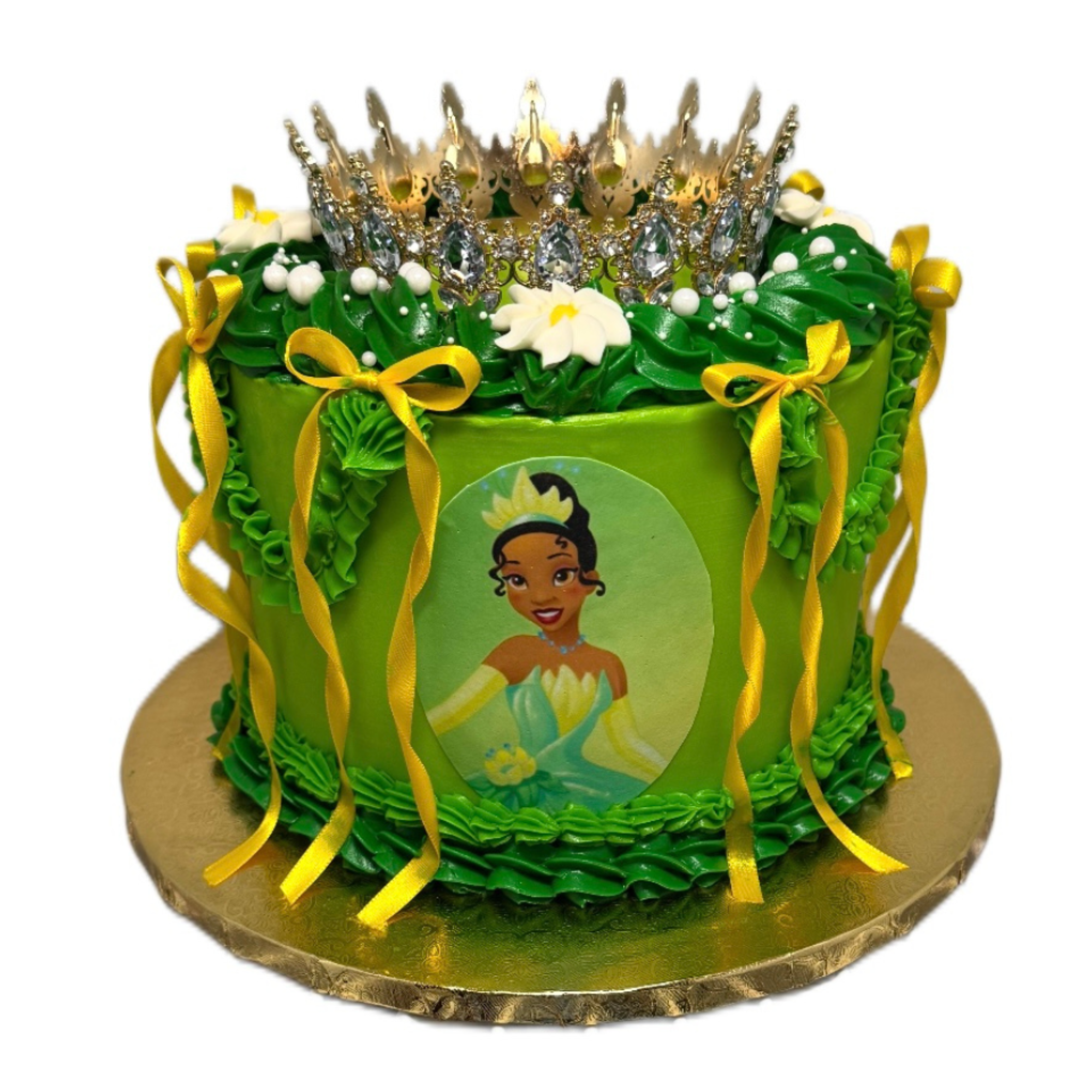 A cake decorated with green icing, yellow ribbons, white flowers, and topped with a tiara.