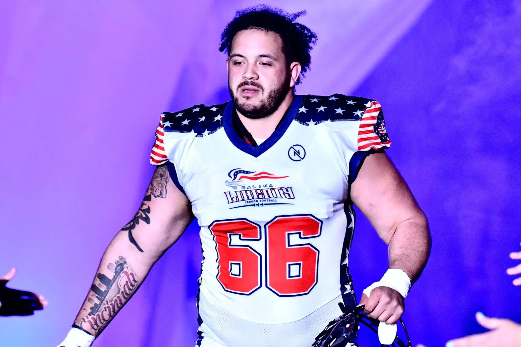 A football player wearing a white, red, and blue Salina Liberty jersey with the number 66, standing against a purple background.