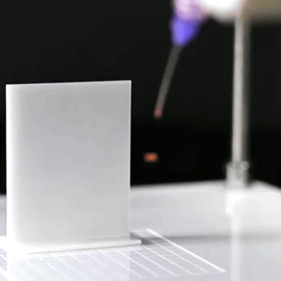 Close-up of 3D printing process with a white square print on a print bed, printing with purple filament.