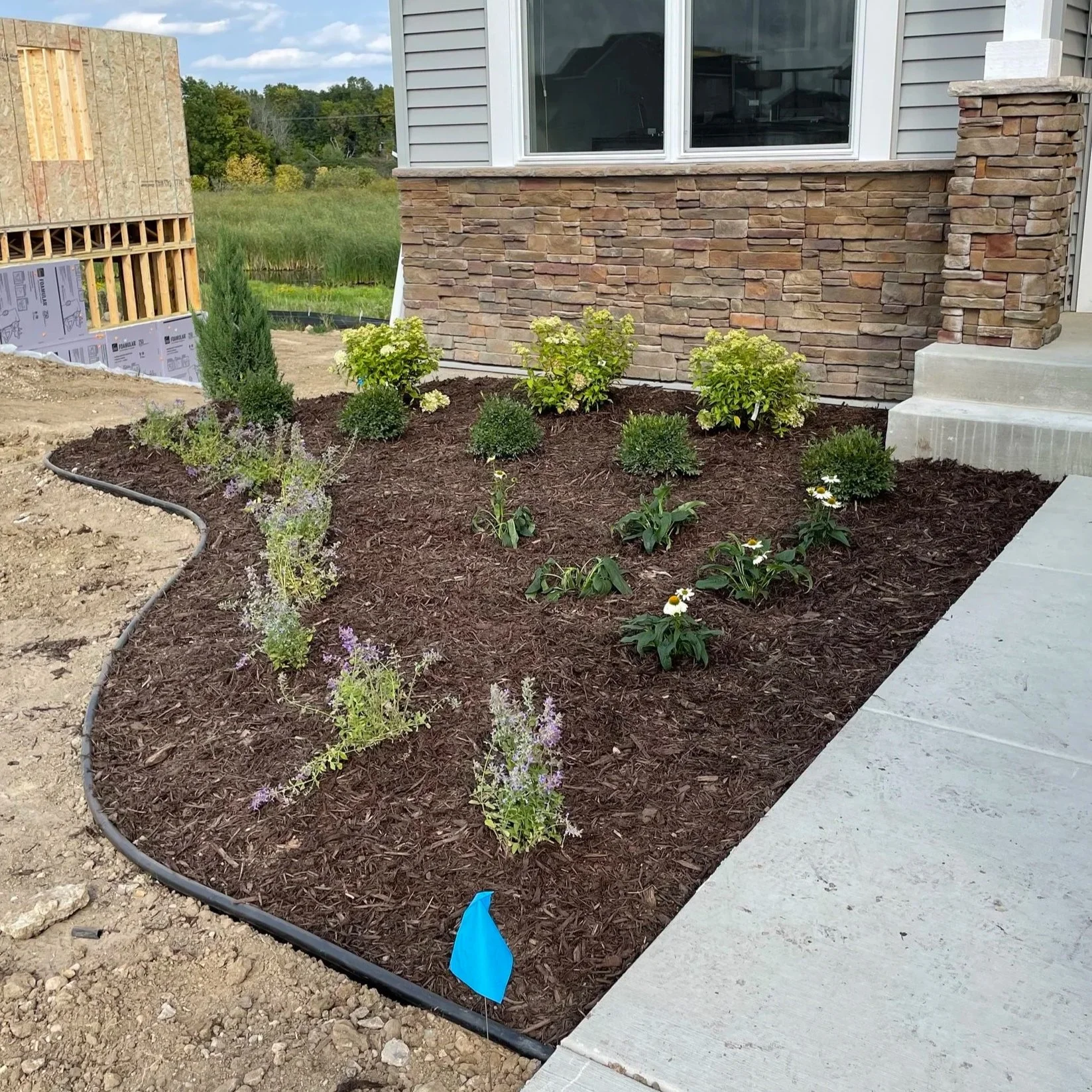Newly constructed home with homeowners adding an extra touch to call it home. Mulch beds with plants. 