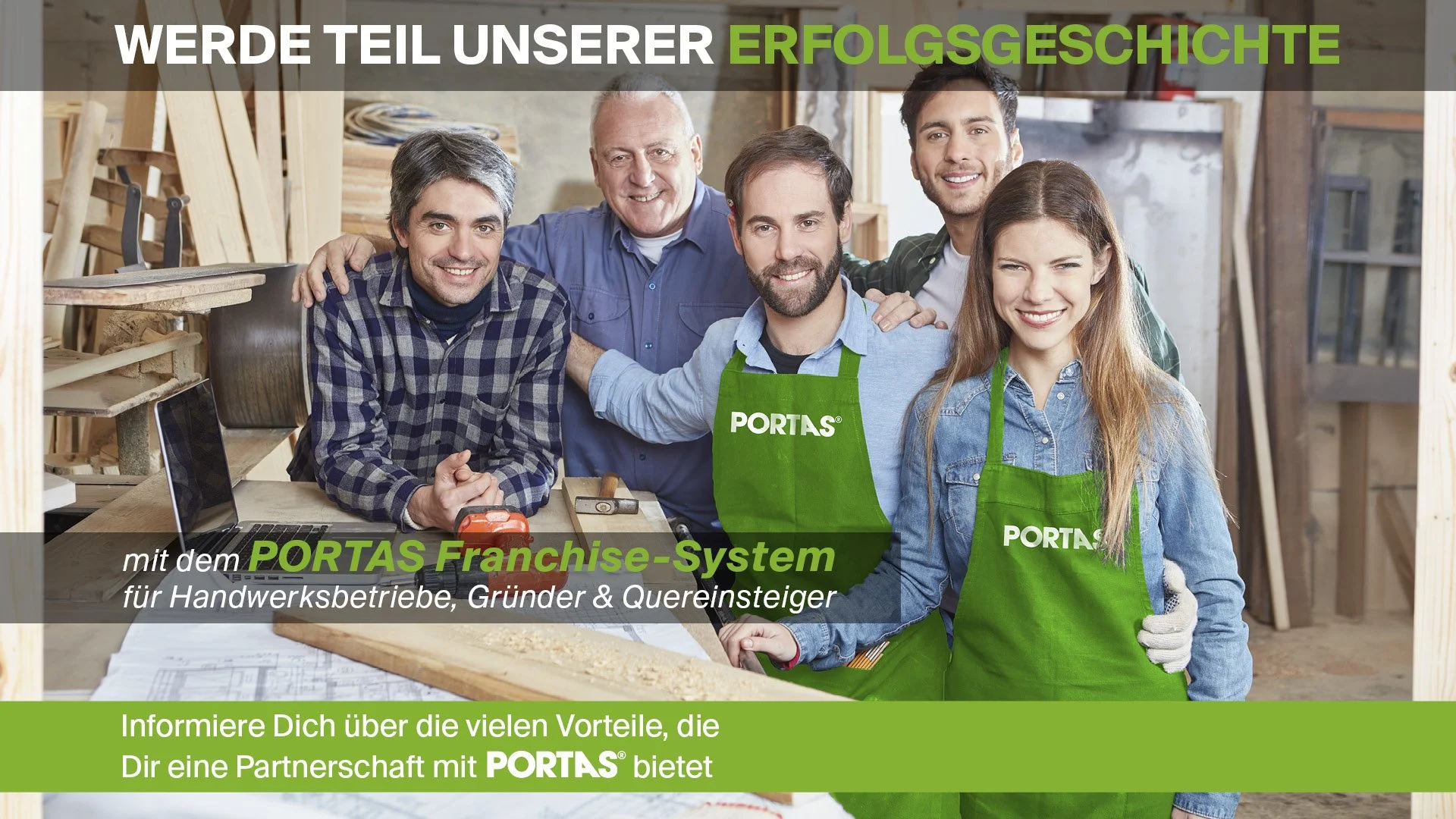 Gruppenfoto von fünf Menschen in einer Werkstatt, von denen zwei grüne PORTAS-Schürzen tragen. Sie lachen und wirken freundlich. Im Hintergrund sind Holzarbeiten und Werkzeuge zu sehen.