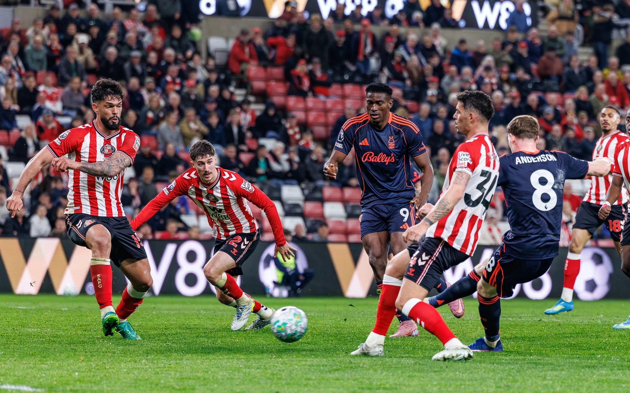 Soccer players in action during a match, with a crowd watching in the background.