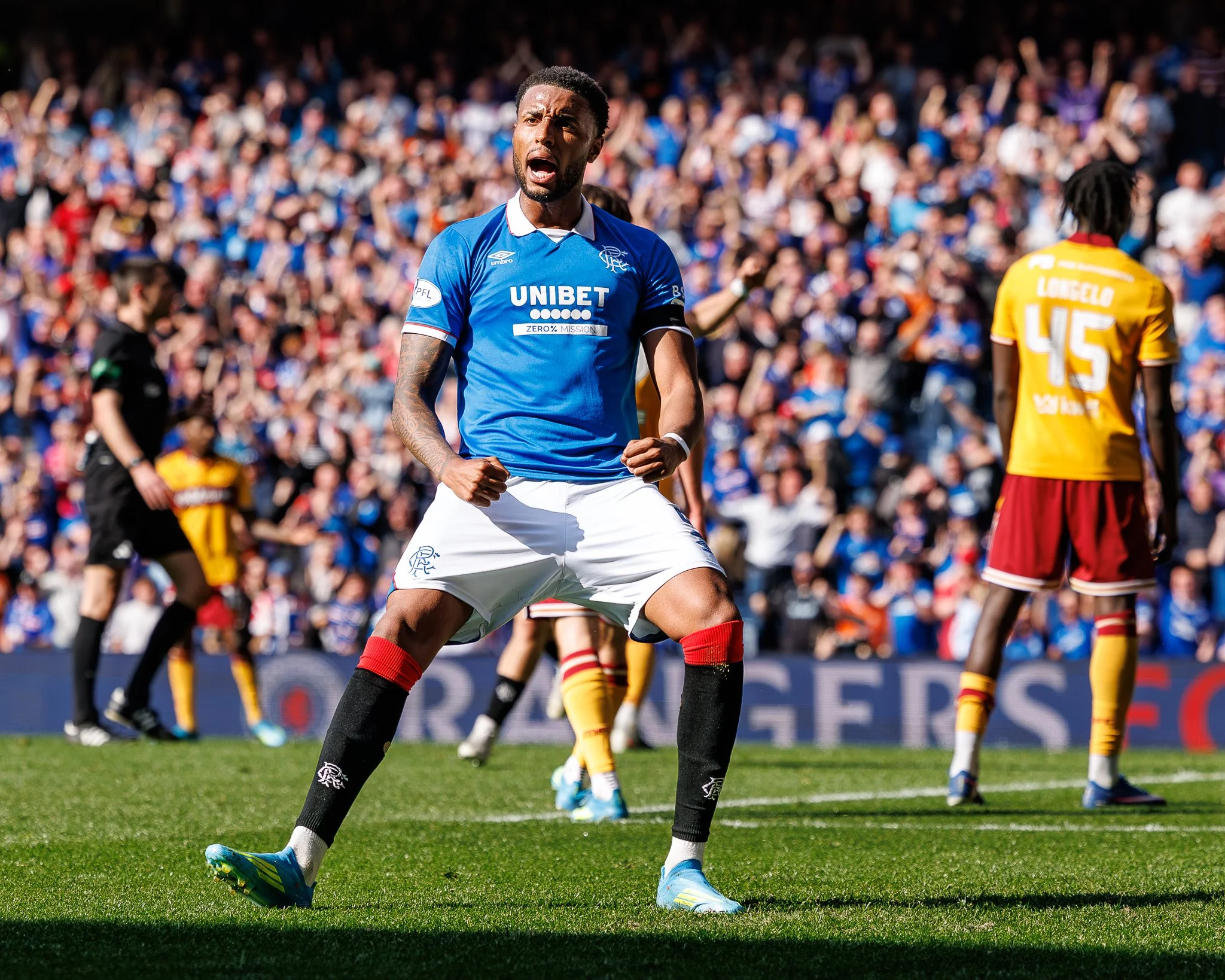 A soccer player in a blue jersey with 'UNIBET' logo, celebrating on the field among other players and a crowd in the background.