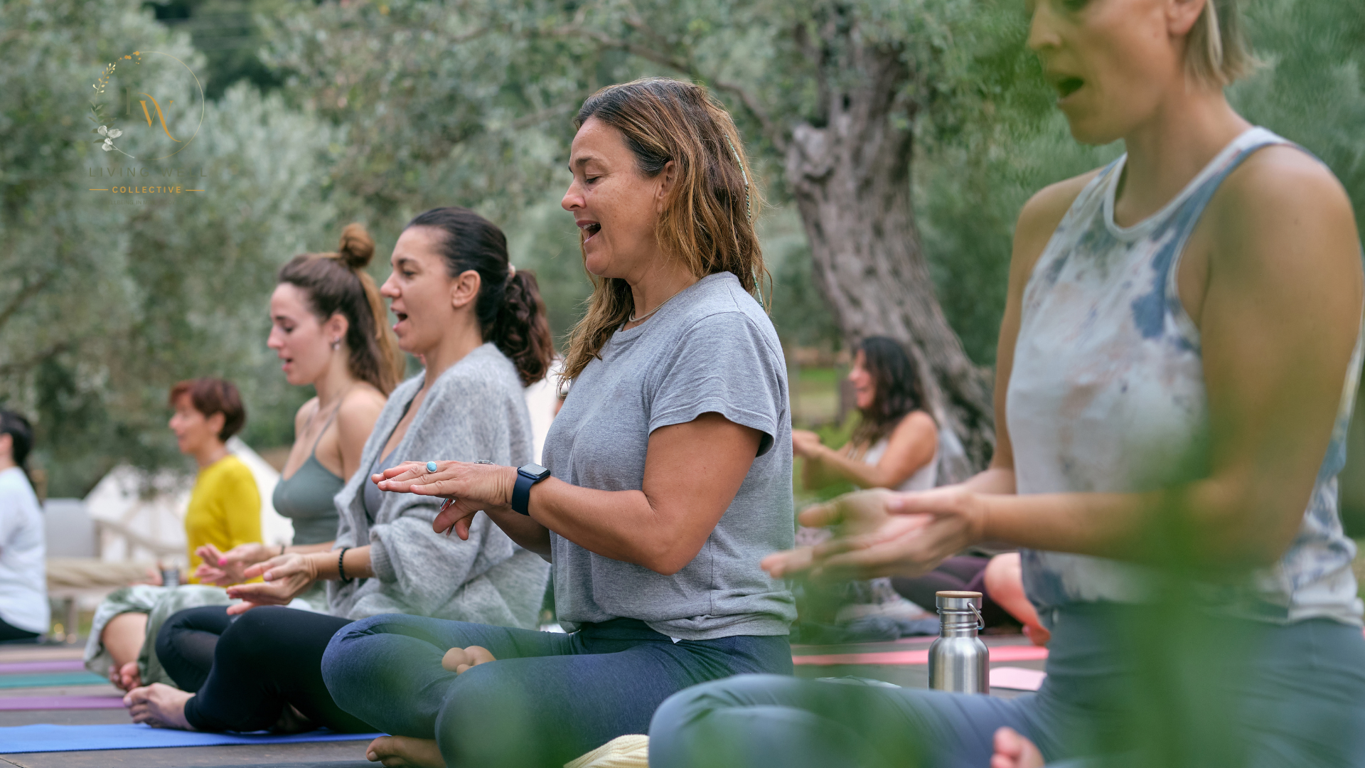 People practicing meditation outdoors on yoga mats during daytime in a park with trees around.