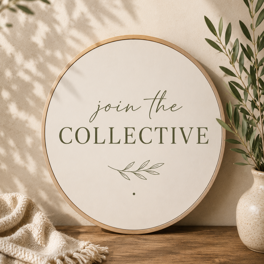Decorative round sign on a wooden surface with the words 'join the COLLECTIVE' and a leaf illustration, surrounded by a plant in a vase and a textured fabric.