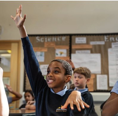 Young student raising hand excitedly in a classroom