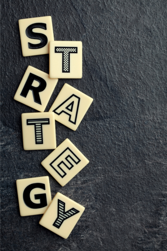 Scrabble tiles spelling out the word 'STRATEGY' on a dark textured surface.