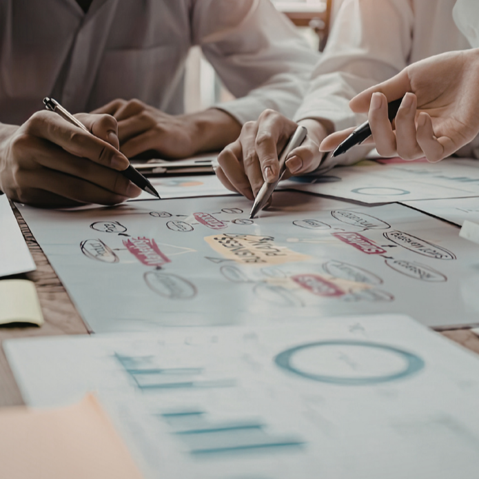 People working together on a business plan or project with markers and charts on paper.