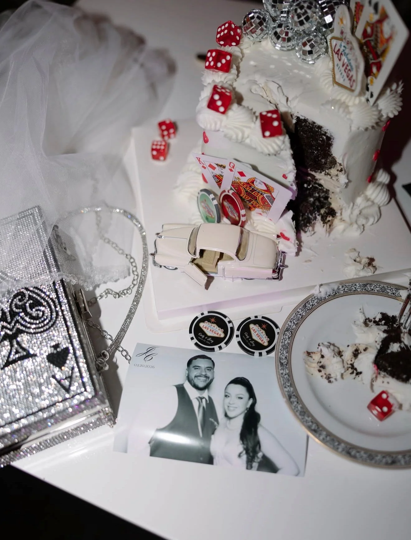 Las Vegas themed decorations, poker chips, and playing cards on a table along with a silver purse, jewelry, a photograph of a couple taken at one of The Dream Booth Co's photobooths