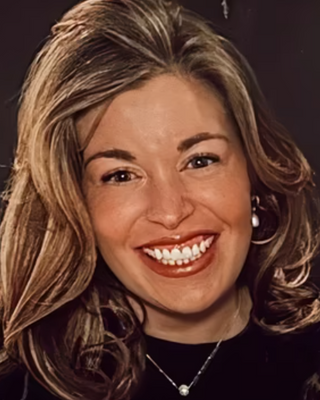 Close-up of a smiling woman with wavy, shoulder-length hair and a black top.