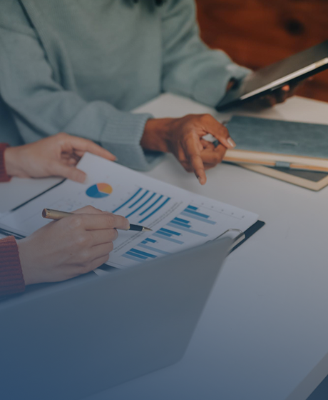 Two people analyzing financial charts and graphs at a table with a laptop and tablet.