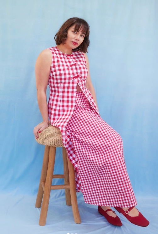Studio product photography of Bonkers Bon Coeur red and white checkered gingham dress on blue backdrop featuring founder Amanda Butten