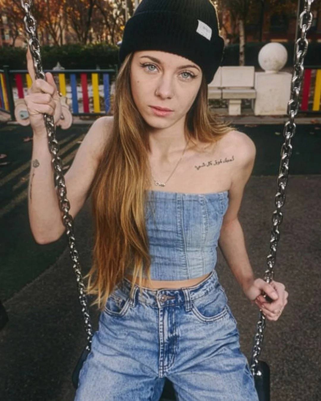 retrato mujer rubia, ojos azules, cabello largo, pelo largo, gorro negro, denim, mezclilla azul, top, jeans, pantalones, crop top, jardín, juegos infantiles, columpio, chica jugando, madrid, chica blanca, collar, mini tattoo, tatuaje mini, playground