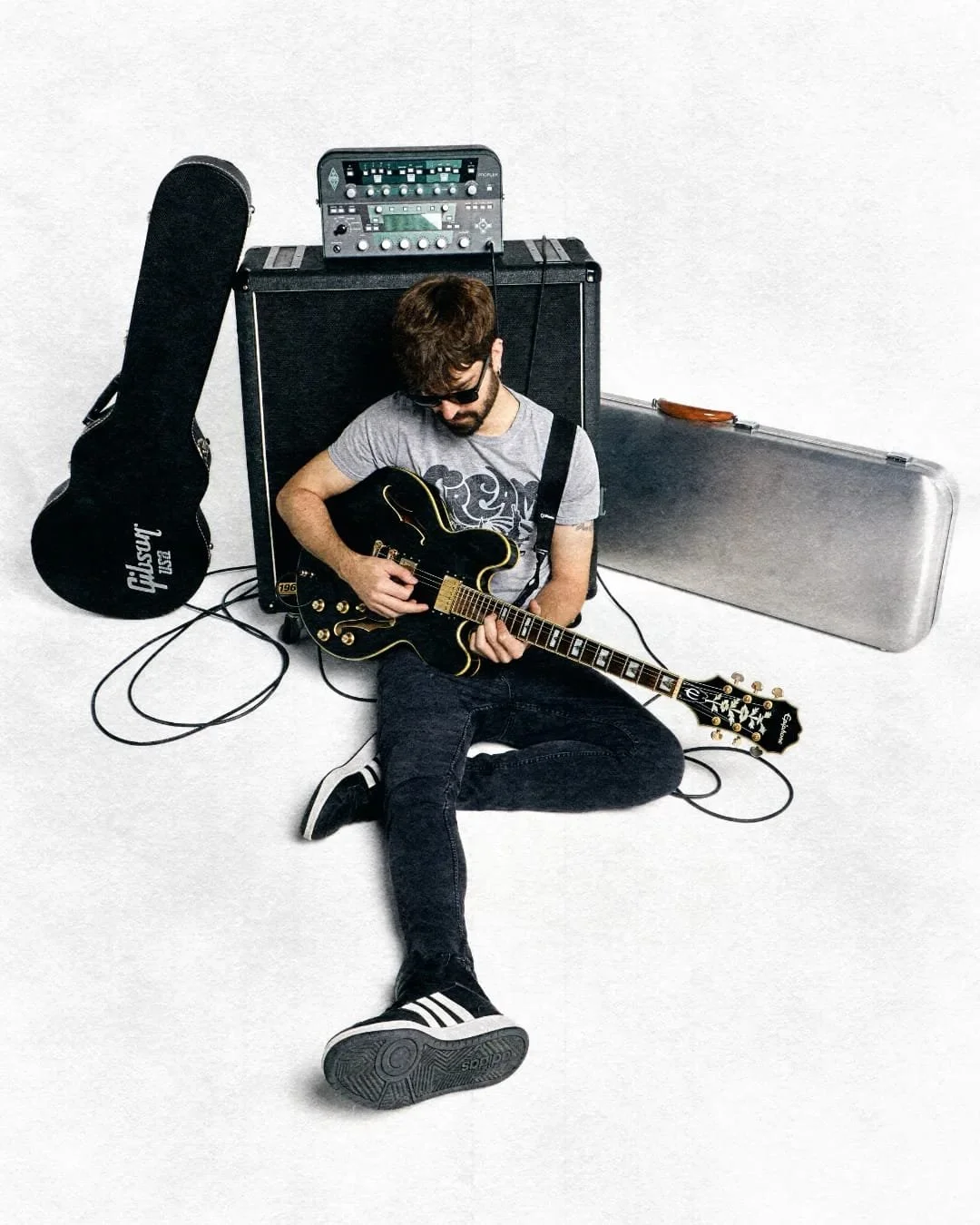 adidas, gibson, retrato músico joven en el suelo, rock foto, guitarra negra, amplificadores, foto alternativa rock, revista música, chico rockero, músico, guitarrista, madrid, fondo blanco foto, clases guitarra, estuche metálico, chico con barba