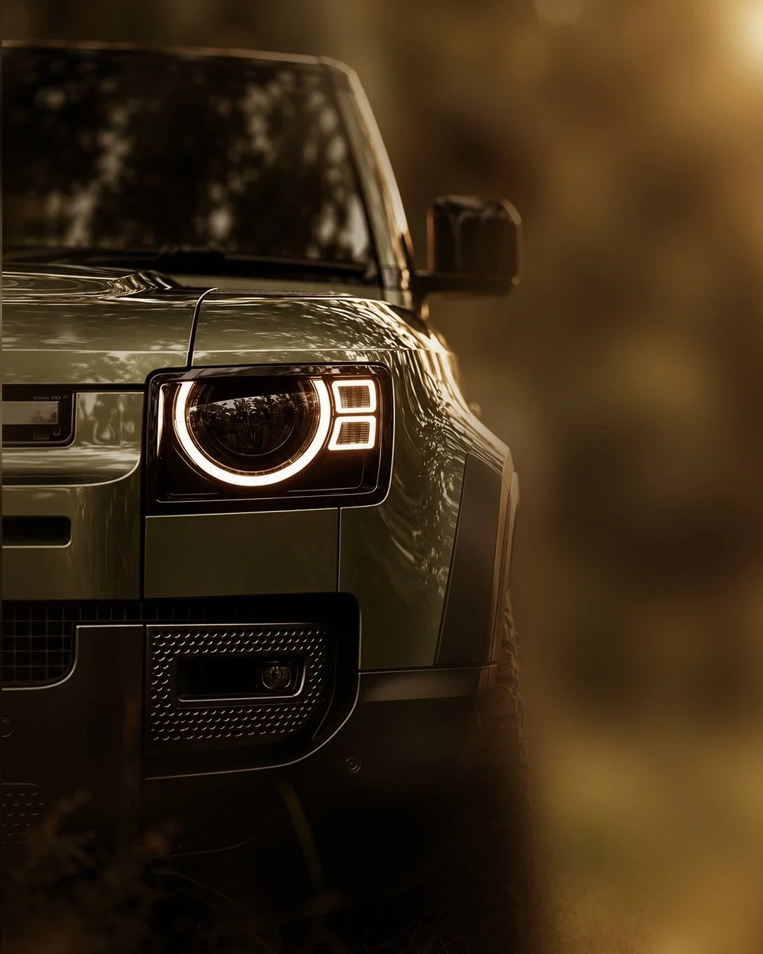 Close-up of the front of a dark-colored SUV with a round headlight with an LED ring, parked outdoors during sunset.