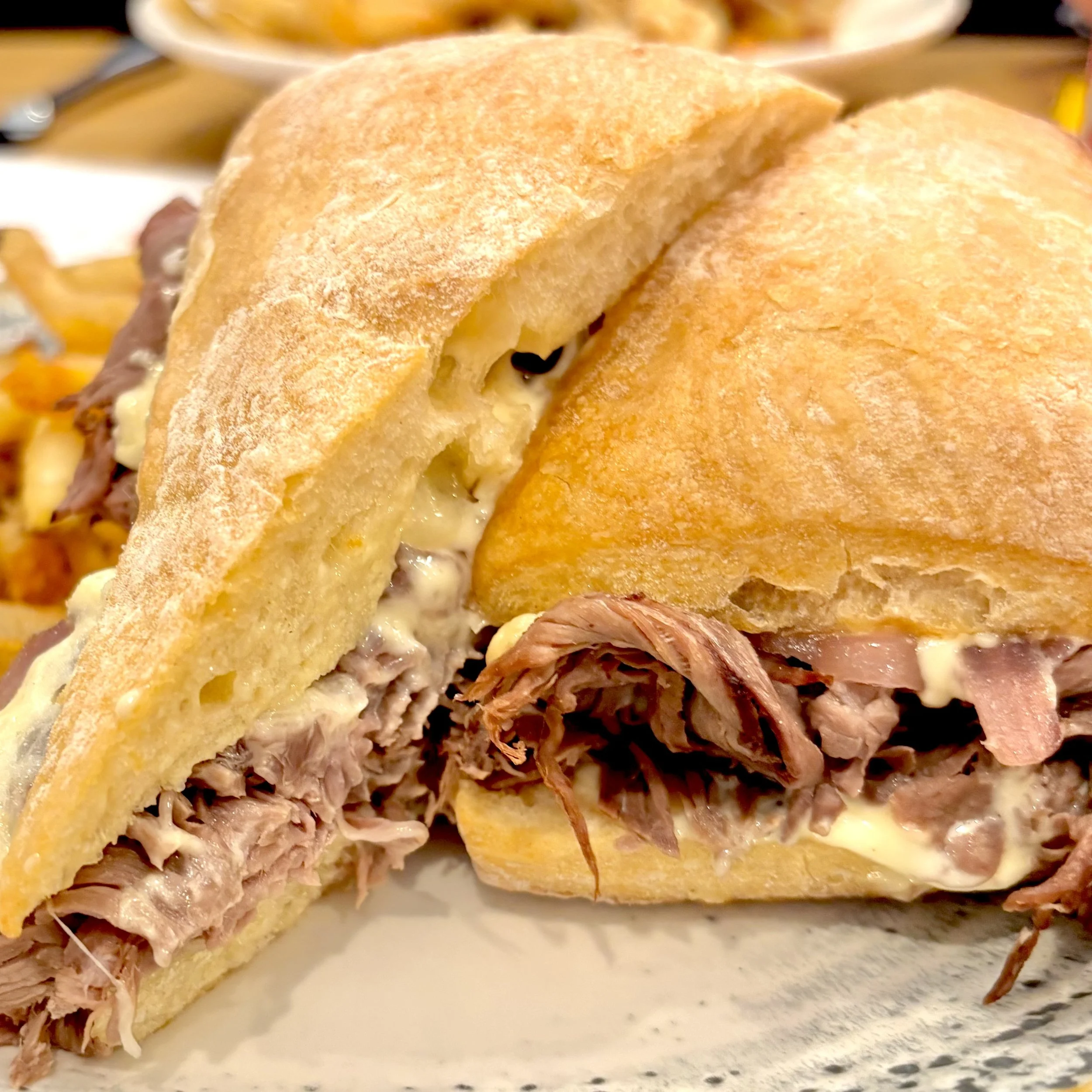 Close-up of a sandwich with shredded pork, melted cheese, and sandwich bread.