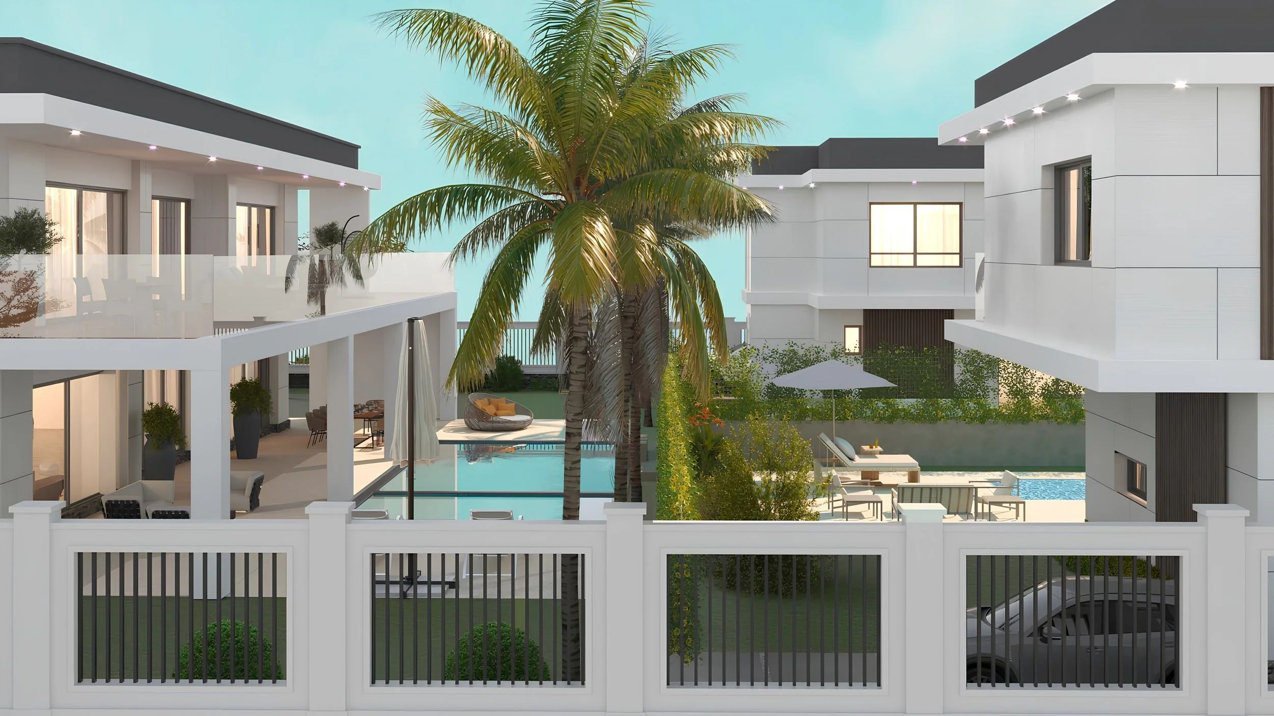 Modern white residential buildings surrounding a pool area with outdoor seating, palm trees, and greenery, viewed through a white fence.