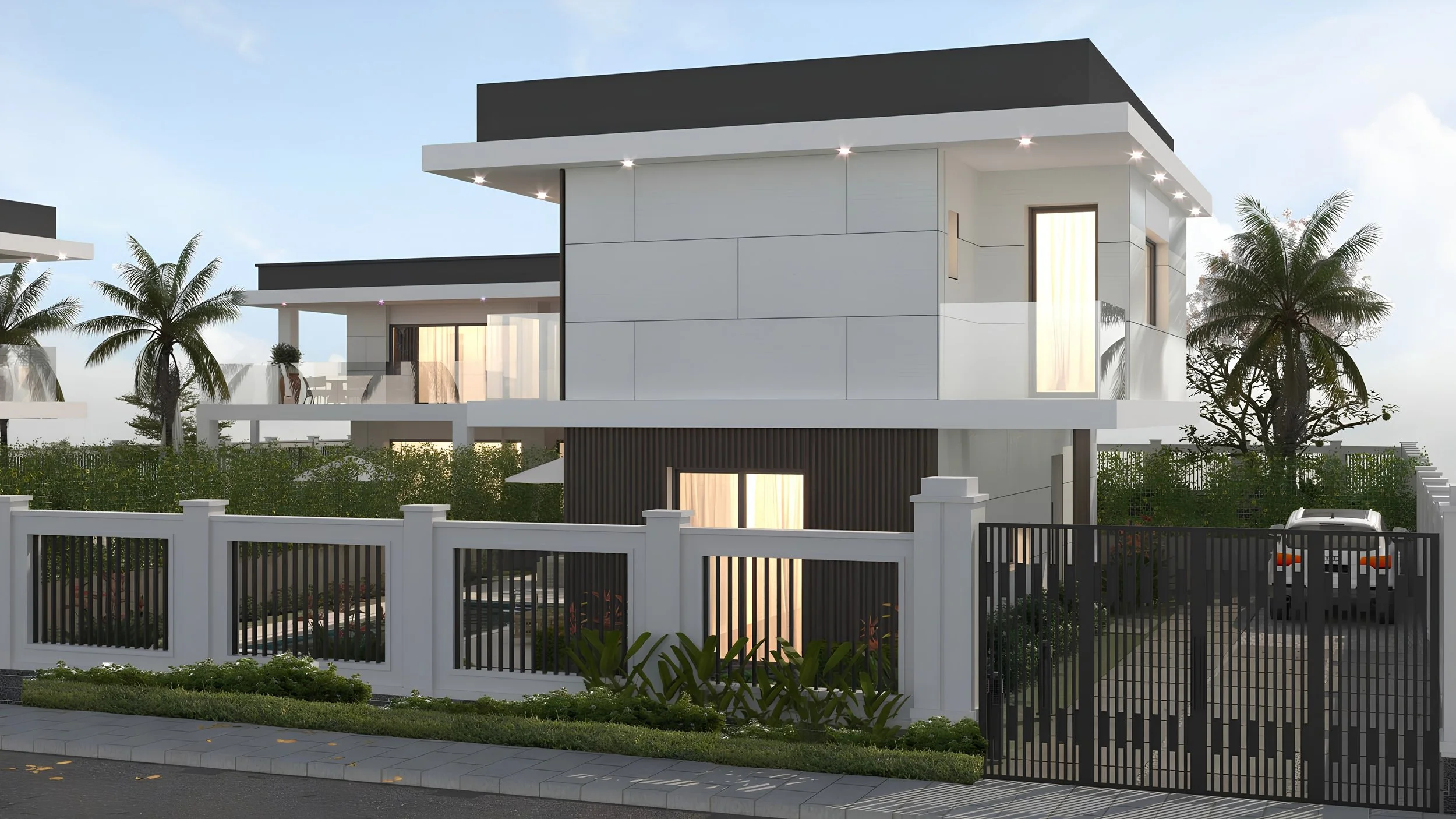Modern white multi-story house with large glass windows, surrounded by a white and black fence, palm trees, and a garden, under a blue sky.