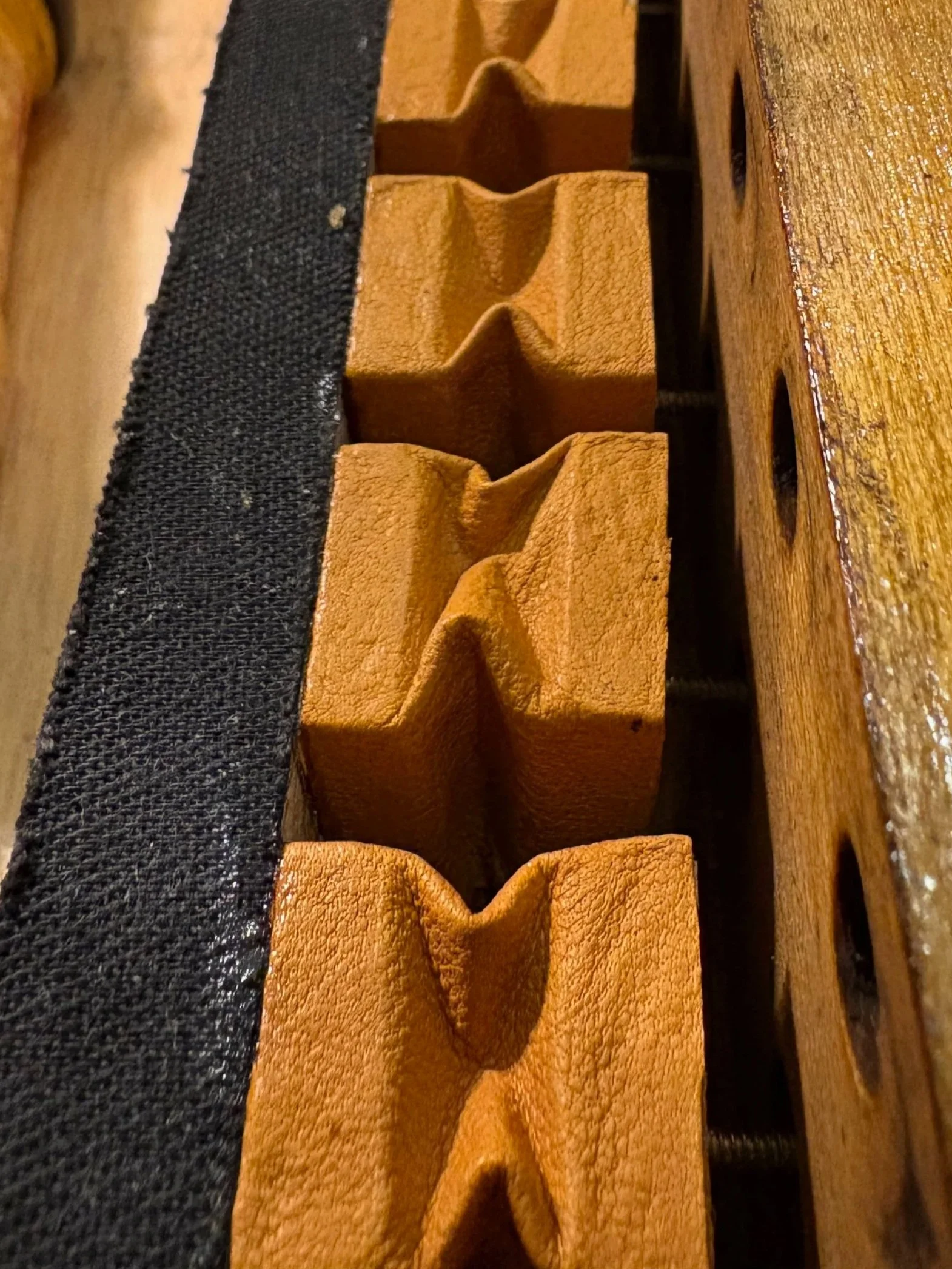 Close-up of a wooden table with a black cloth and a row of four leather covered pneumatics.