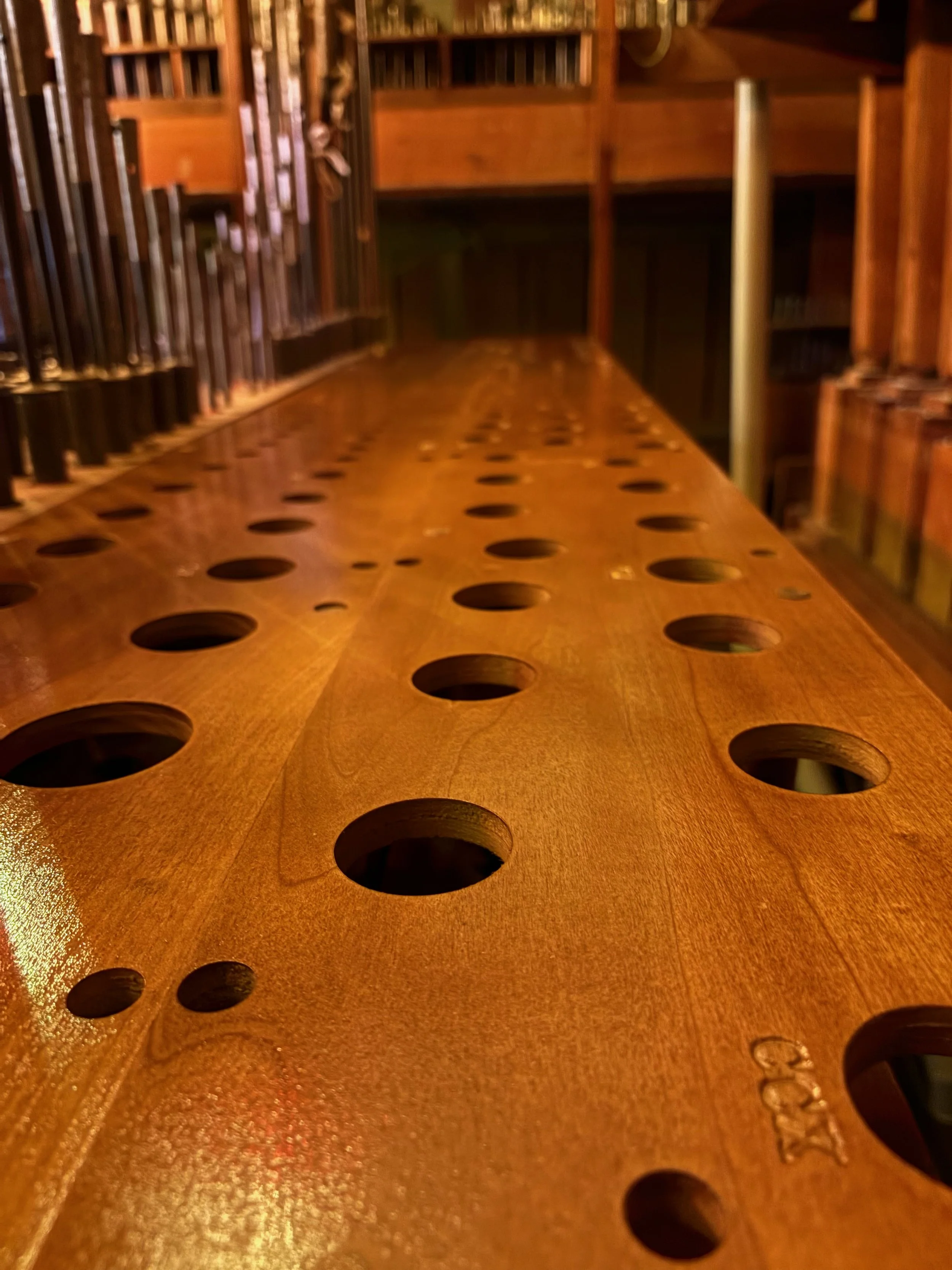 Close-up of a wooden rack board with various circular holes and text 'CCX' visible in the bottom right corner.
