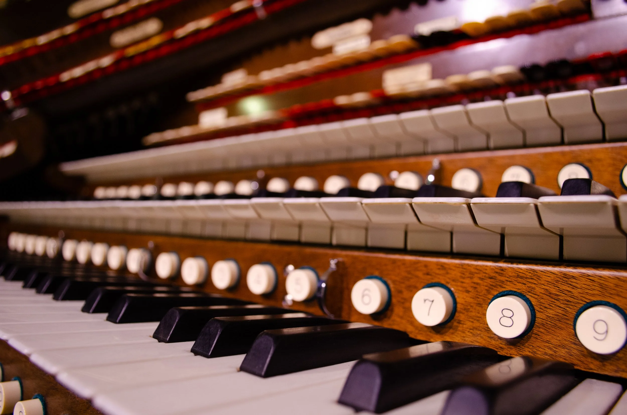 Close-up of vintage pipe organ keys showing black and white keys with wooden casing.