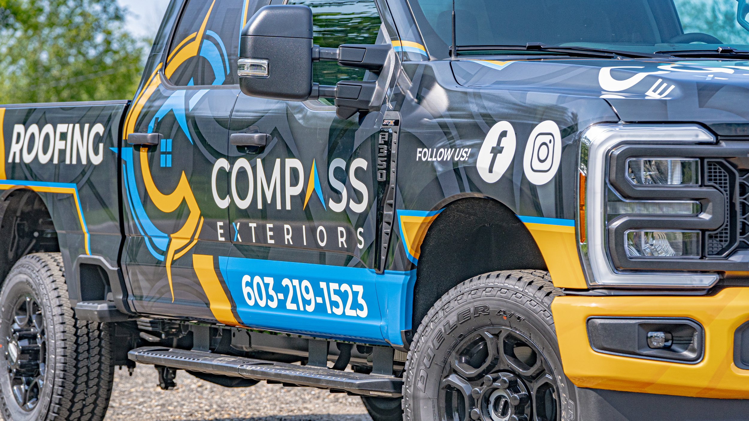 A company vehicle for Compass Exteriors with a colorful wrap design, displaying the company's name, contact number, and social media icons, parked outdoors.
