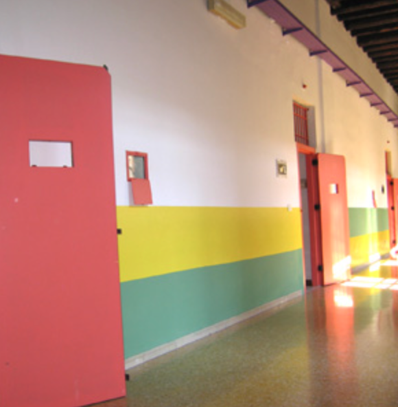 Corridoio scolastico colorato con porte rosse, pareti gialle e verdi e pavimento lucido
