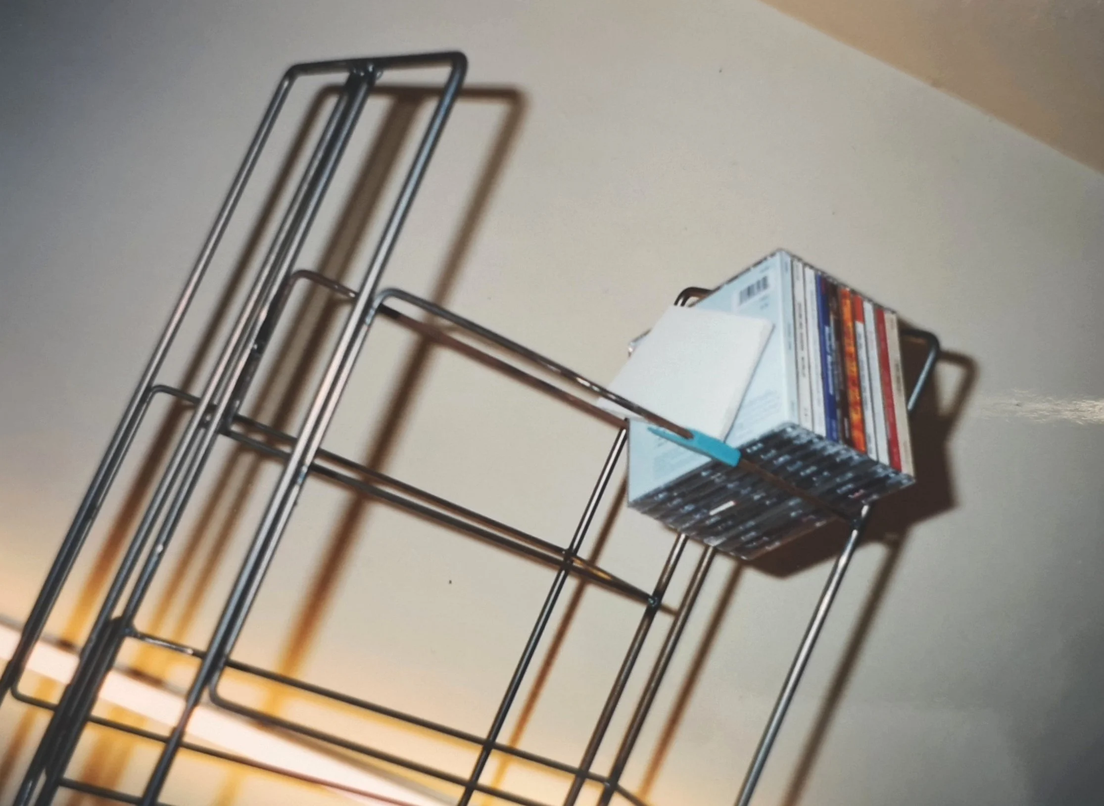 Portariviste metallico nero con riviste e libri appoggiato a una parete.