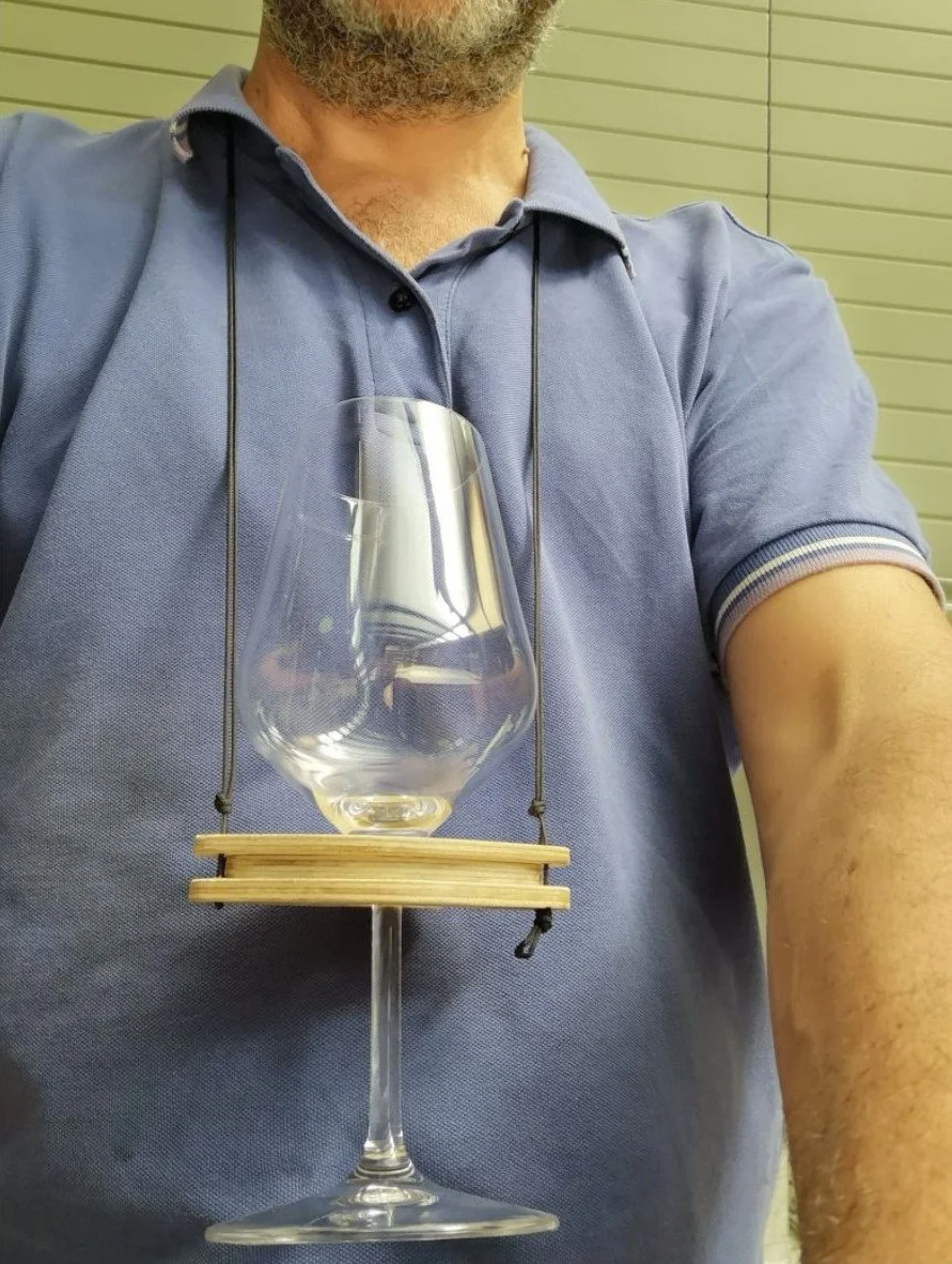 Uomo con polo blu che indossa un supporto artigianale per calice da vino vuoto