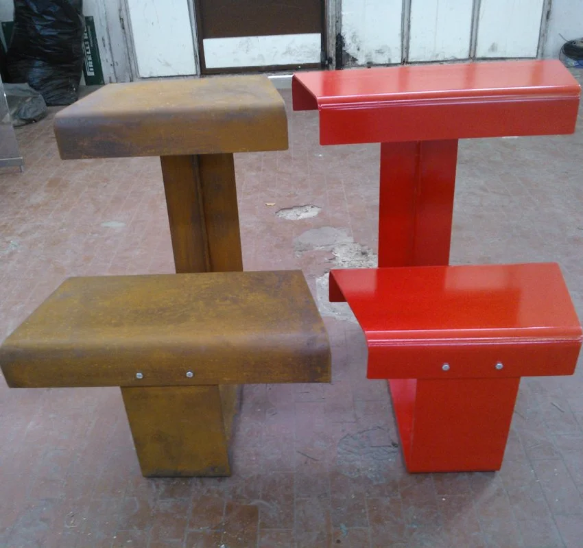 Due panche da esterno in legno, una marrone e una rossa, con sedute e schienali rettangolari.
