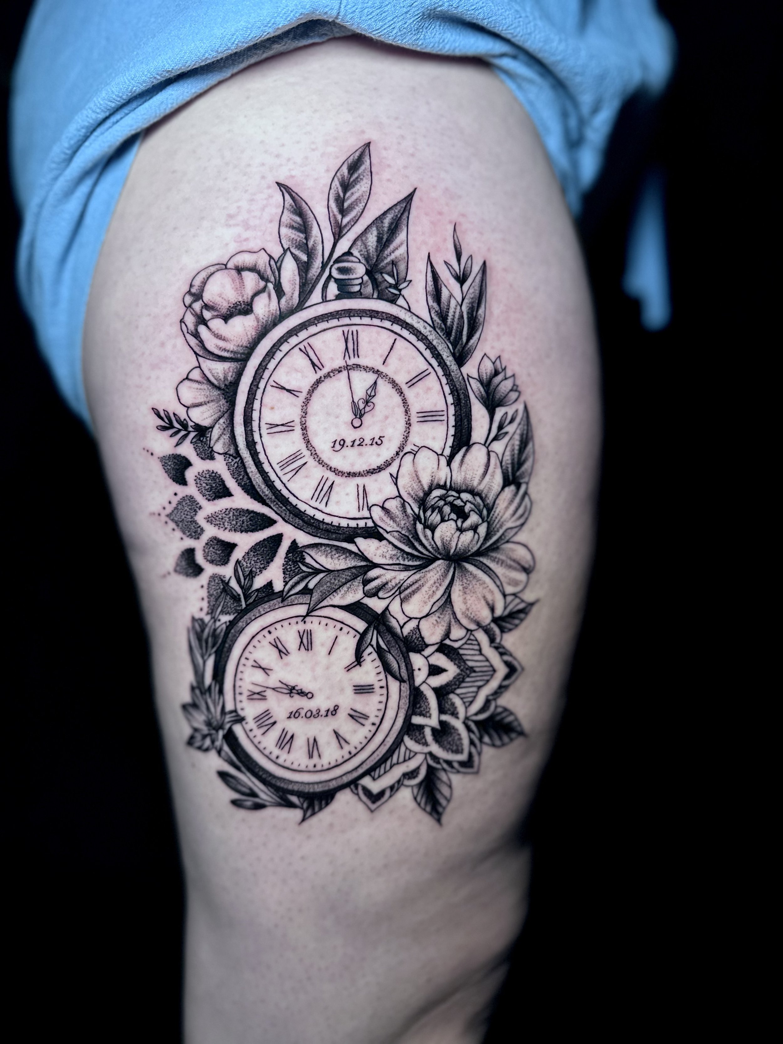 Black and gray tattoo of multiple pocket watches with flowers and leaves on a person's upper arm.