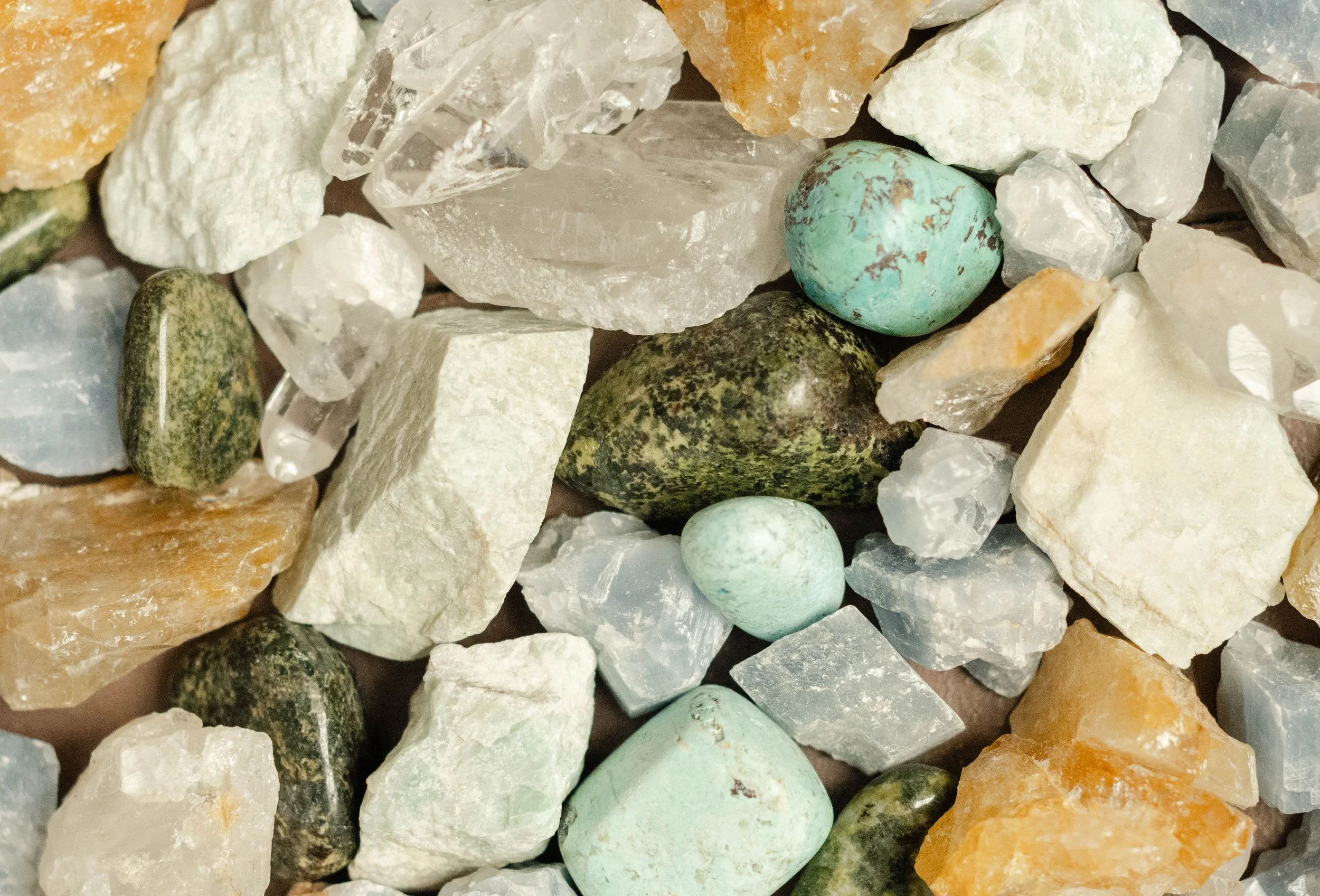 A collection of various small rocks and minerals, including turquoise, white quartz, and other colored stones.