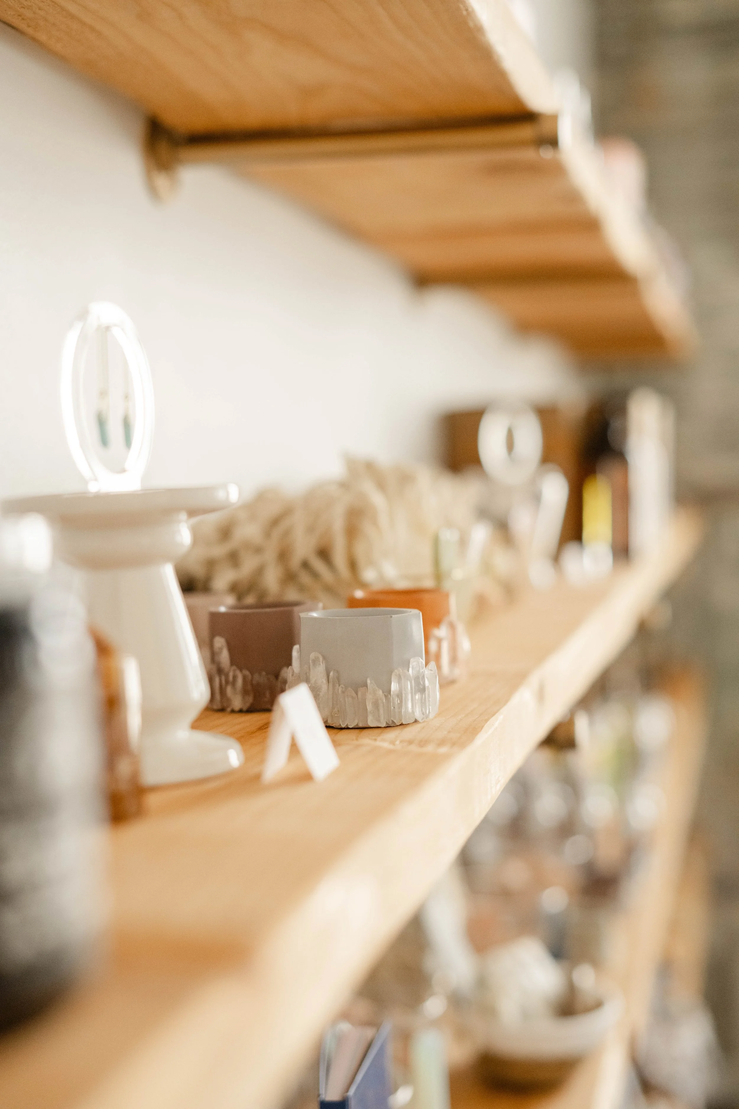 Close-up of a wooden display shelf with various ceramic and pottery items arranged on it, including cups and bowls, with a blurred background.