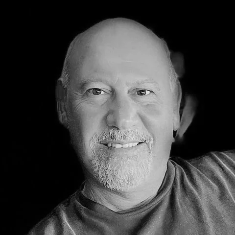Black and white close-up portrait of a smiling middle-aged man with a beard and short hair.