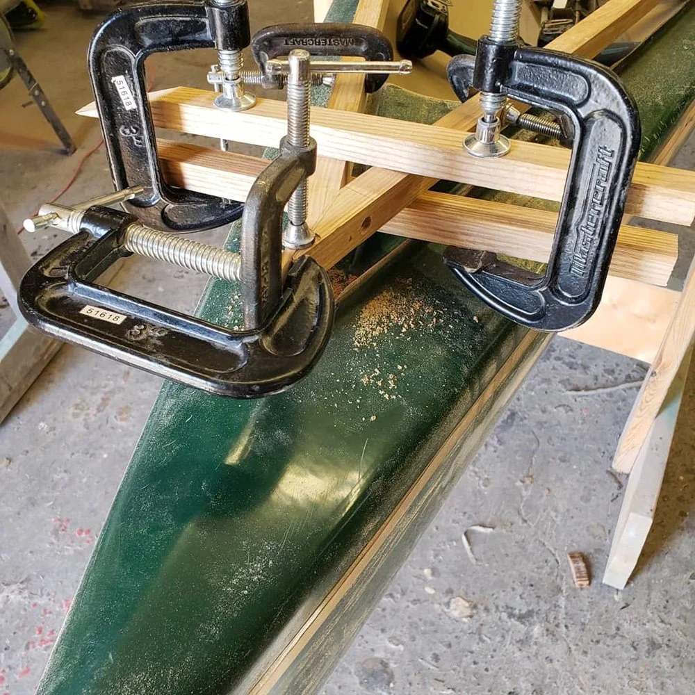 Woodworking clamp holding a wooden piece on a workbench.