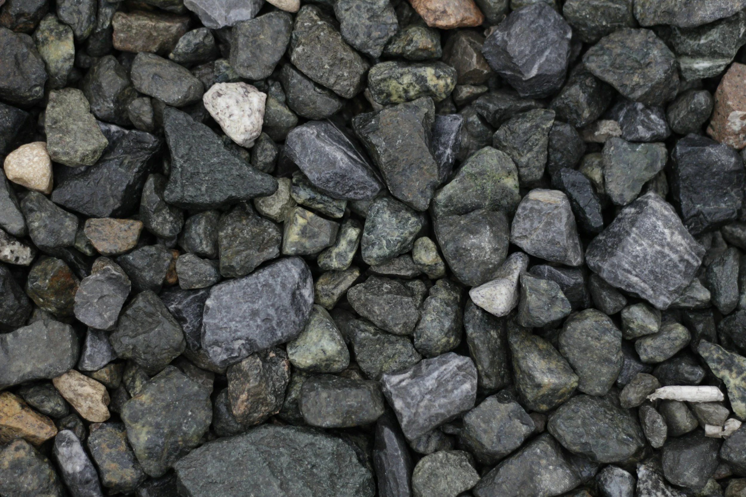 Close-up of small, irregularly shaped gray, black, and white stones or gravel.