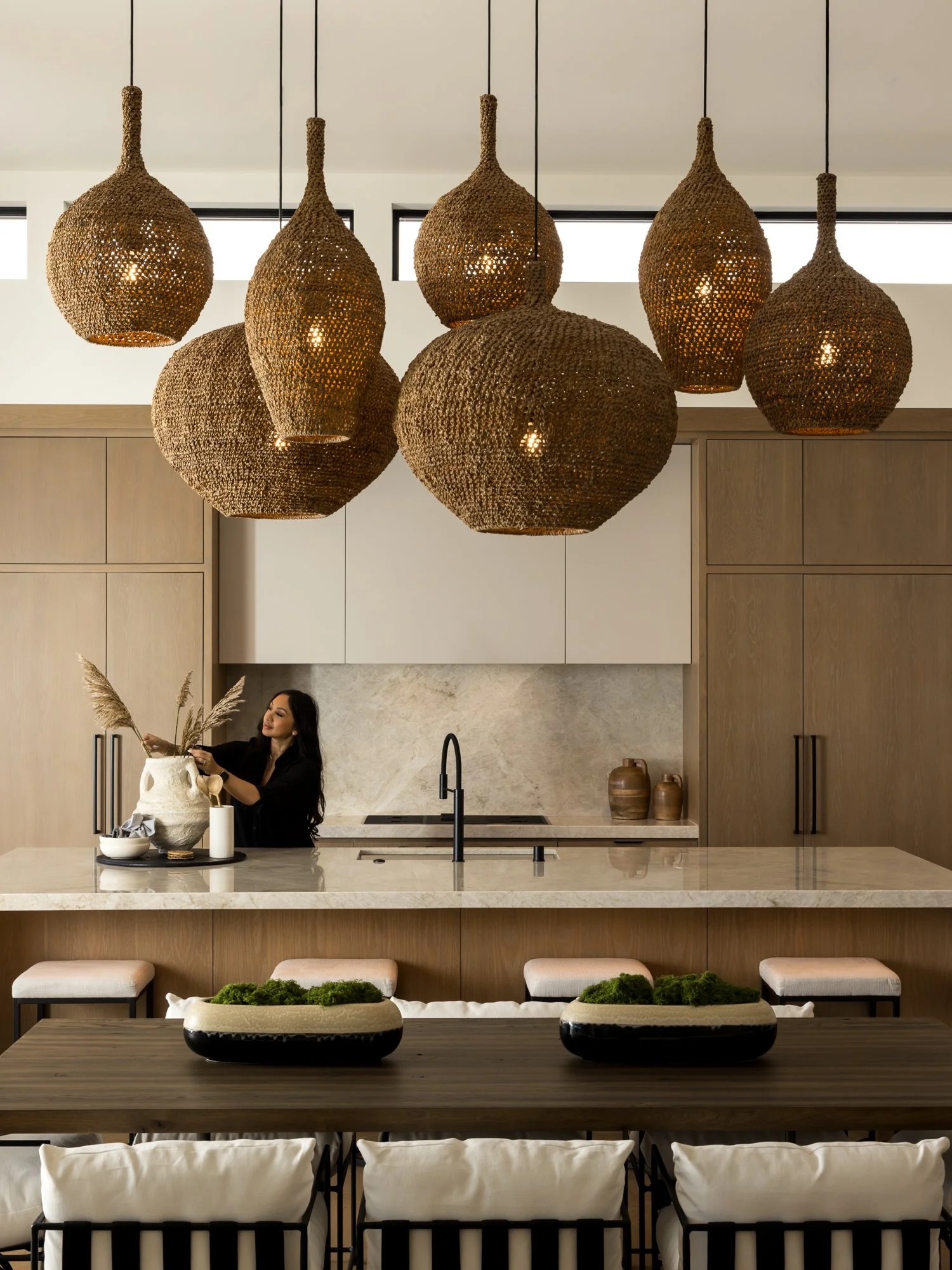 “Warm contemporary kitchen interior with woven pendant lighting and natural wood finishes.”