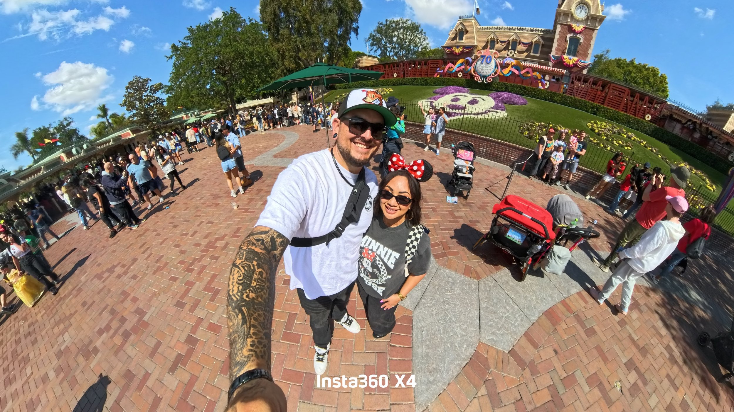 A man and a woman taking a selfie in front of Disneyland's Sleeping Beauty Castle during the park's 70th celebration.
