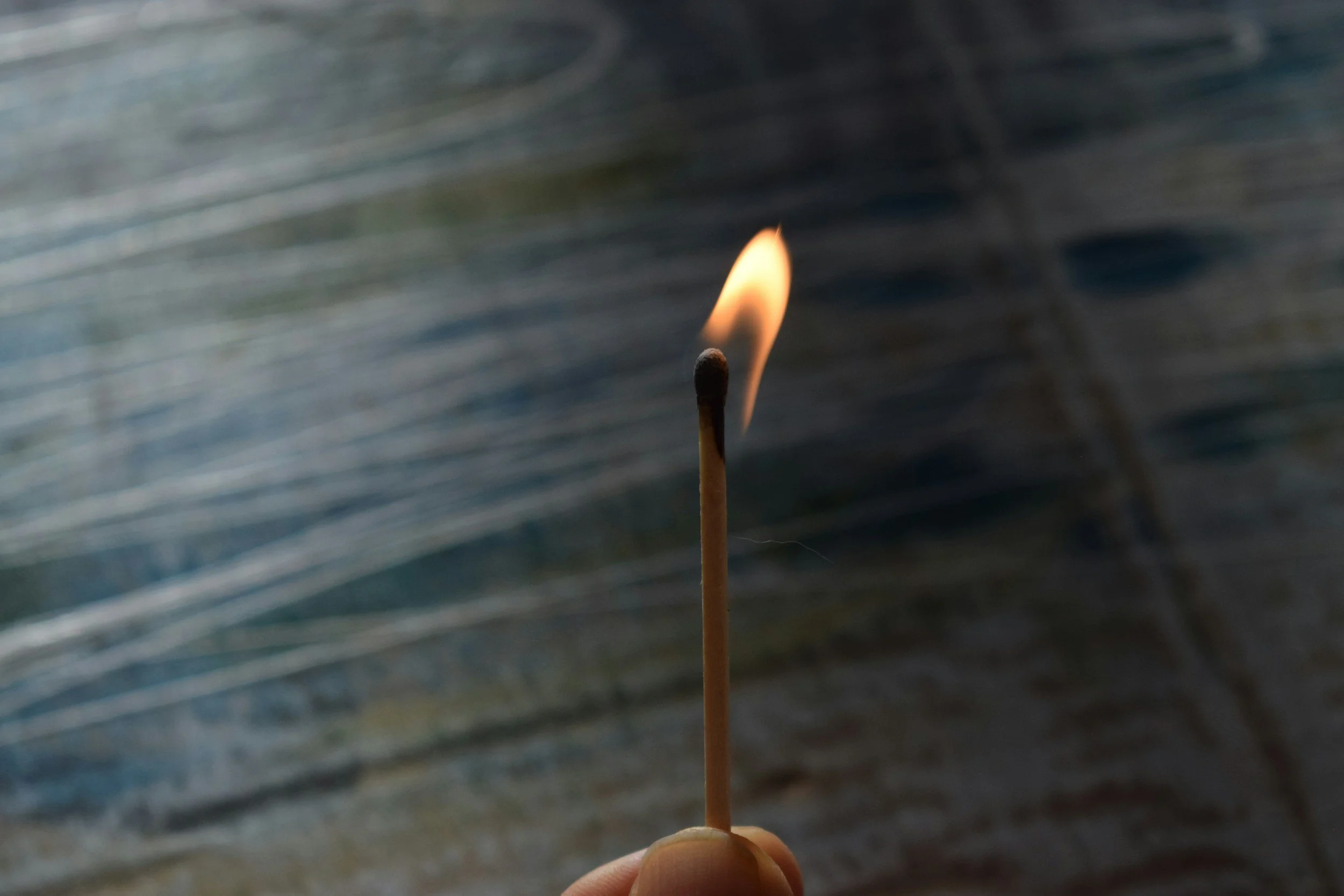 Close-up of a matchstick with a small flame against a blurred background.