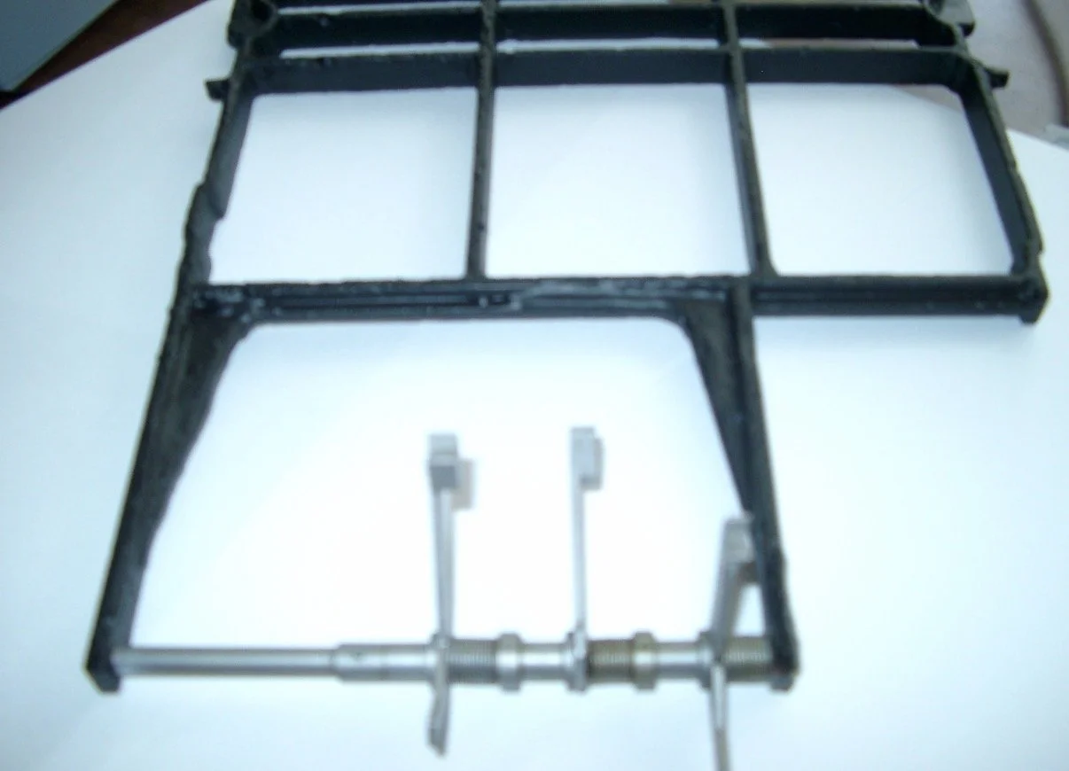 A black metal frame with some screws and hardware parts on a white surface.