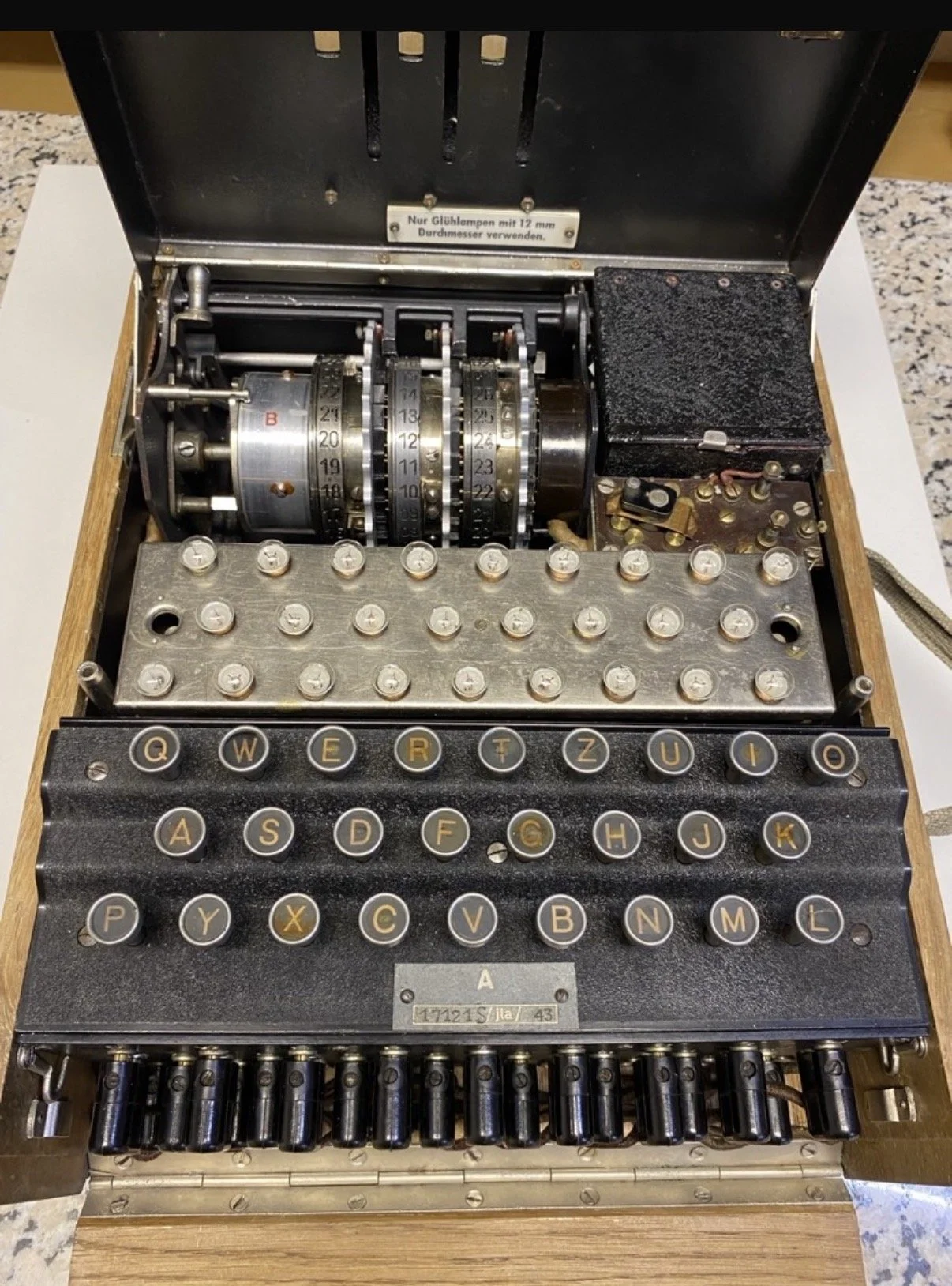 Vintage mechanical cipher enigma machine with rotary dials, a keyboard with round keys, and a metal base for encryption and decryption of messages.