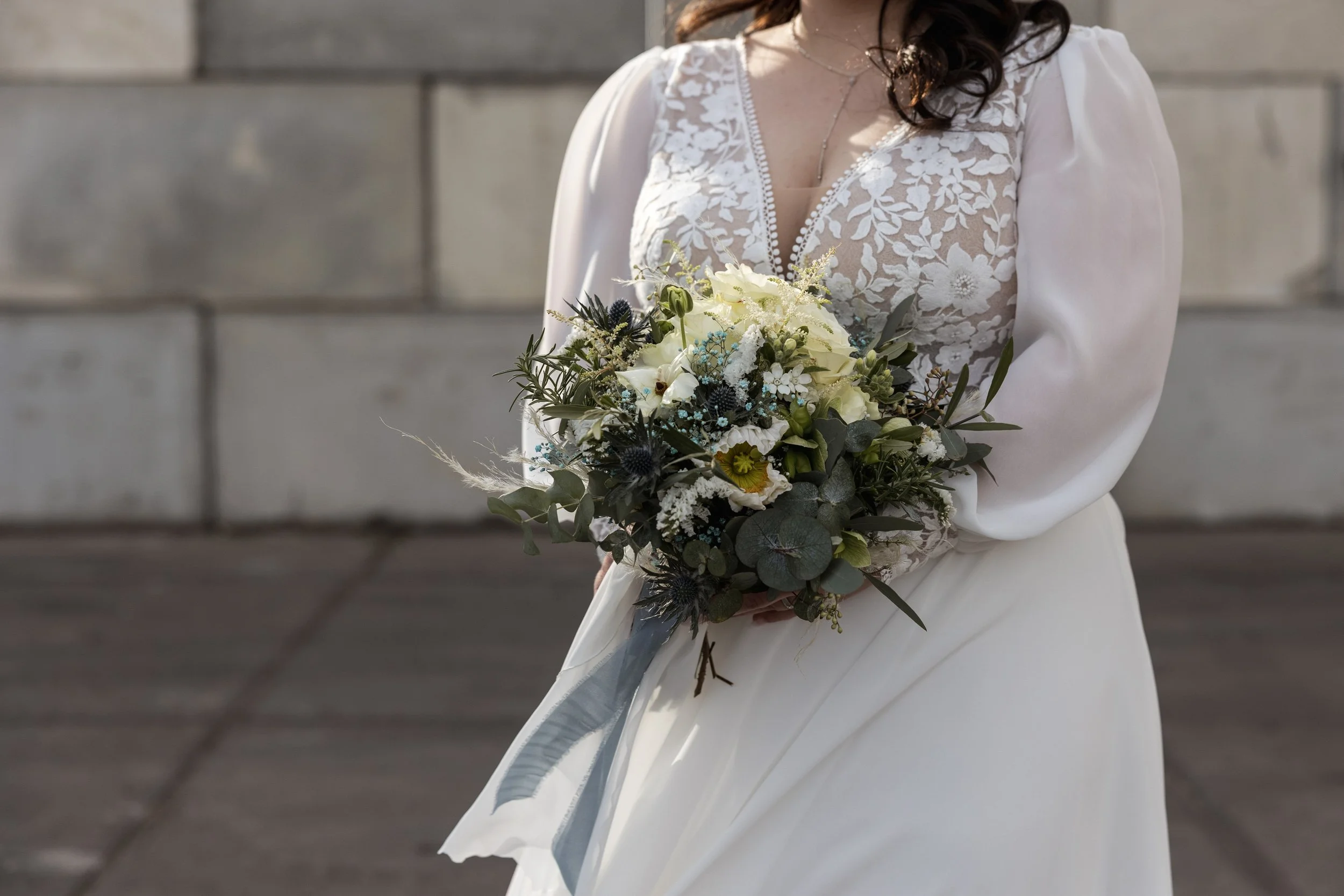 Frau in weißem Brautkleid hält einen Blumenstrauß bei einer Hochzeitsfeier.