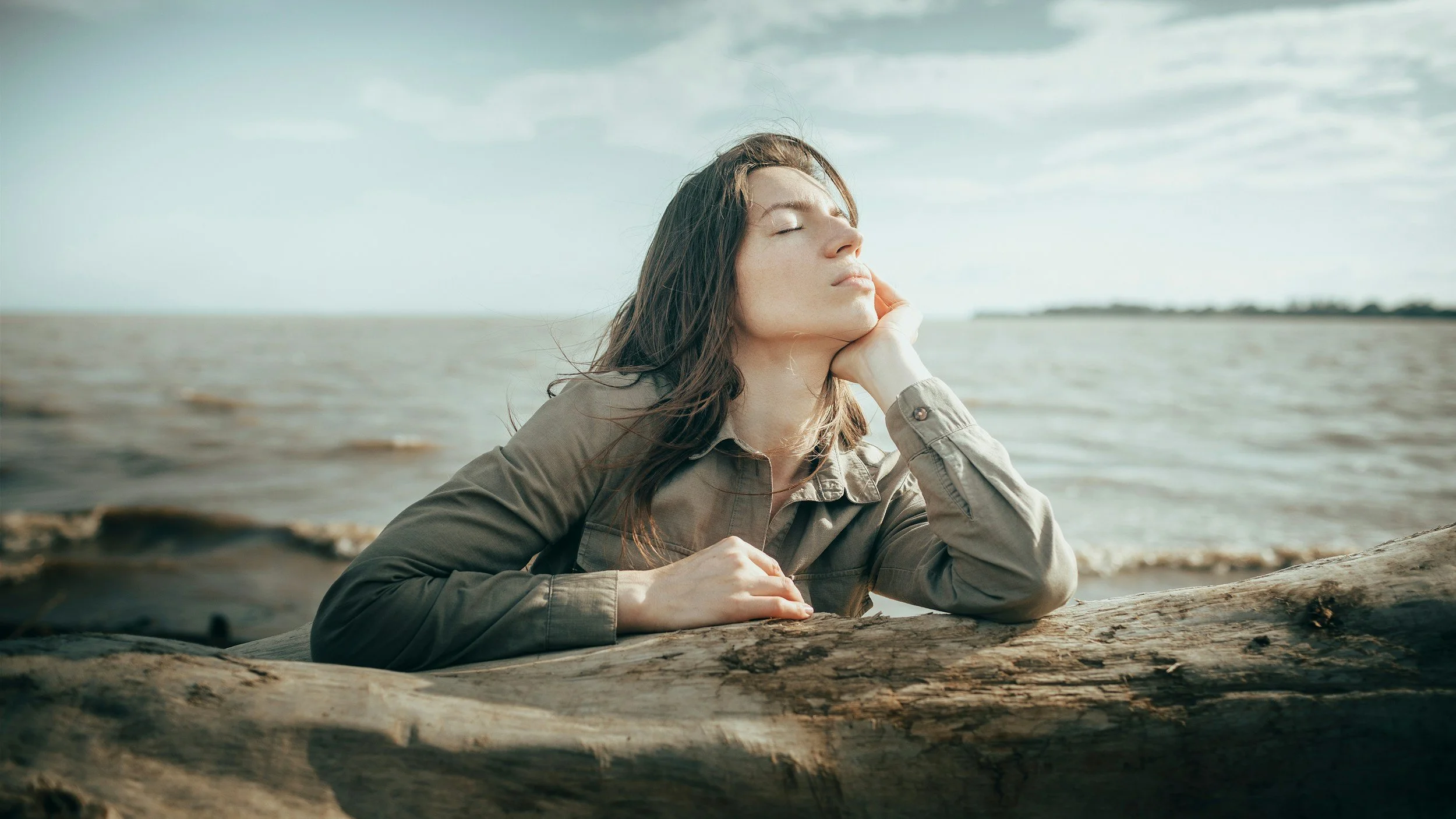 woman eyes closed, leaning on rocks reflectively